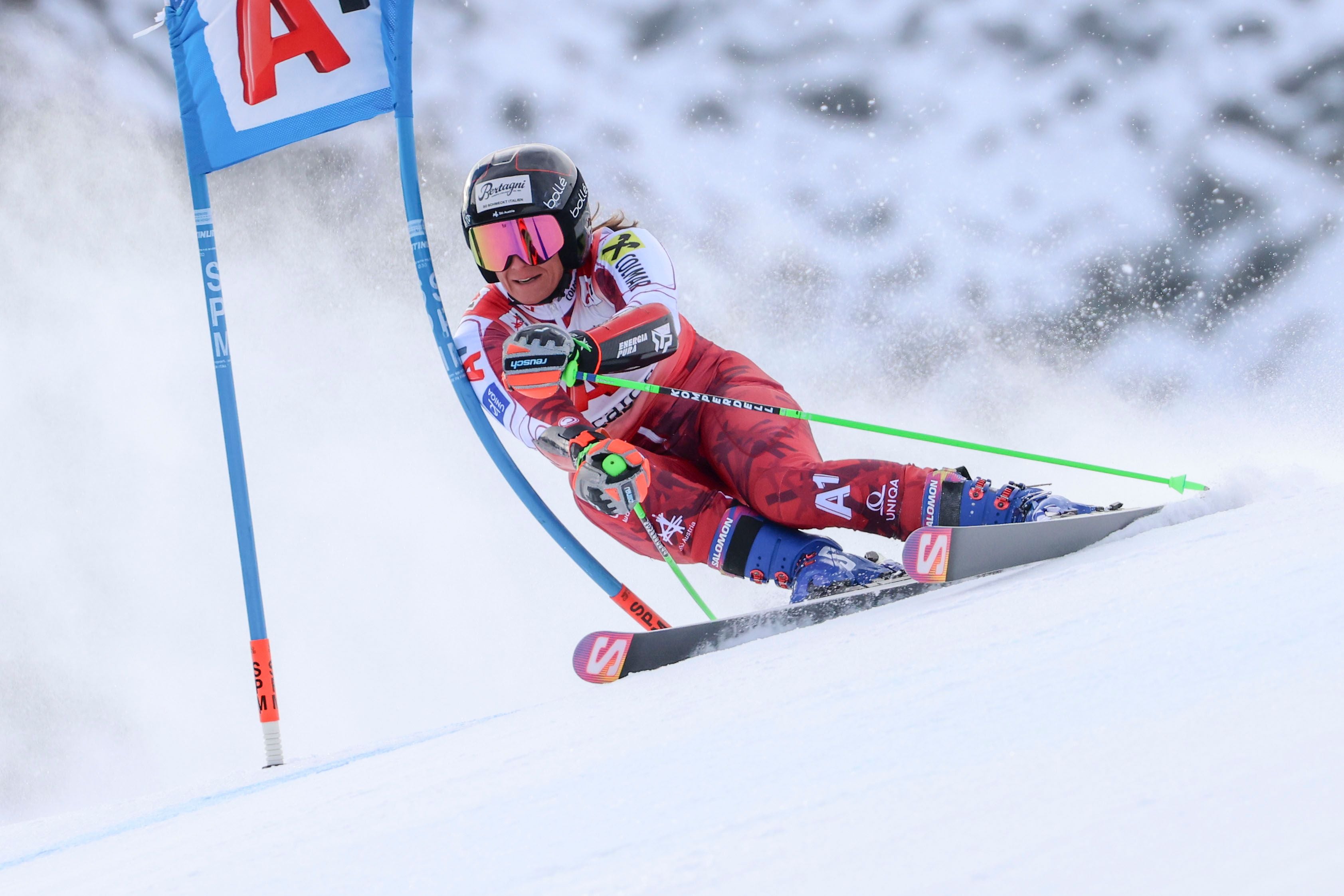 Eine Skirennläuferin fährt beim Riesenslalom mit hoher Geschwindigkeit um ein Tor.