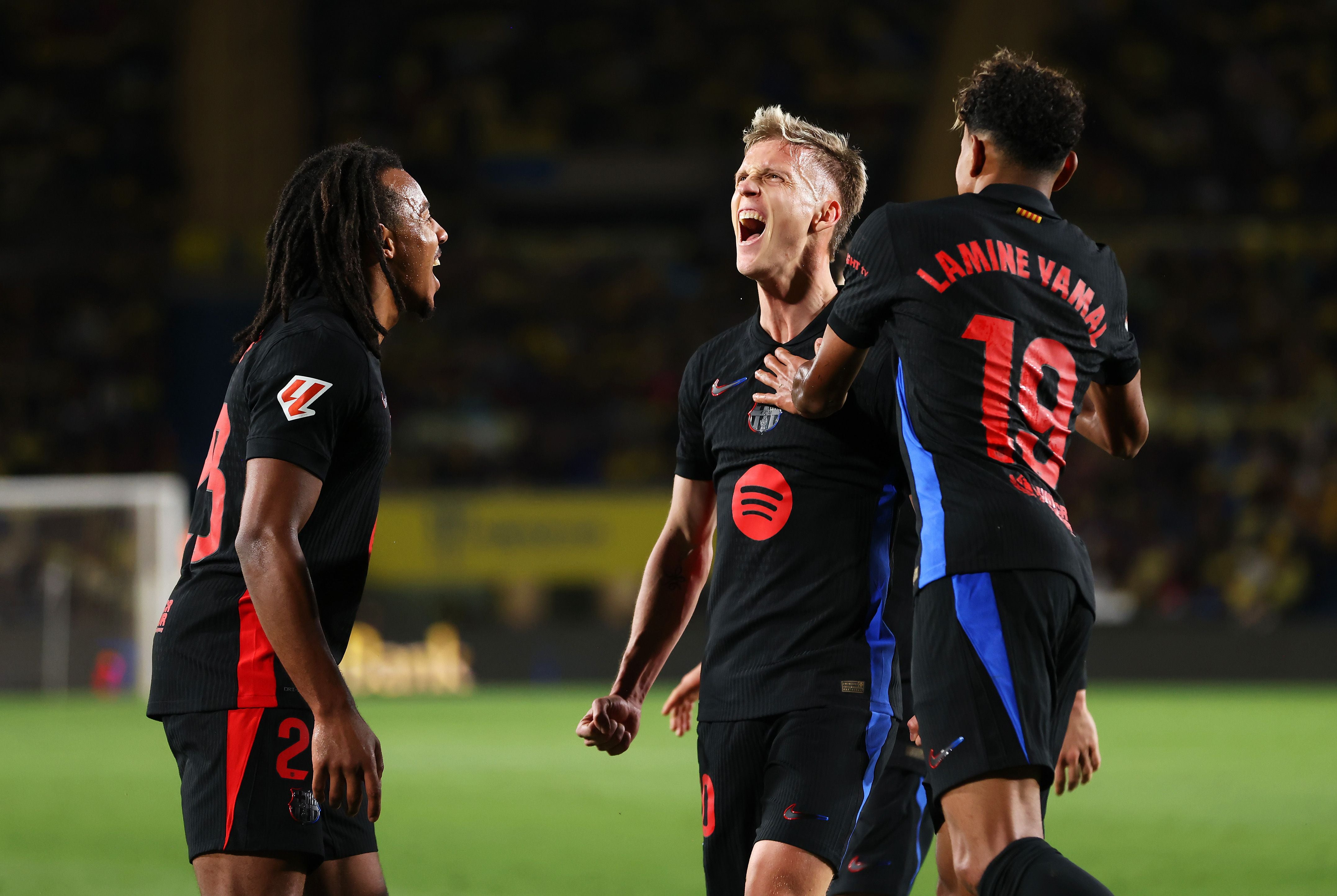 Drei Fußballspieler vom FC Barcelona jubeln gemeinsam auf dem Spielfeld.