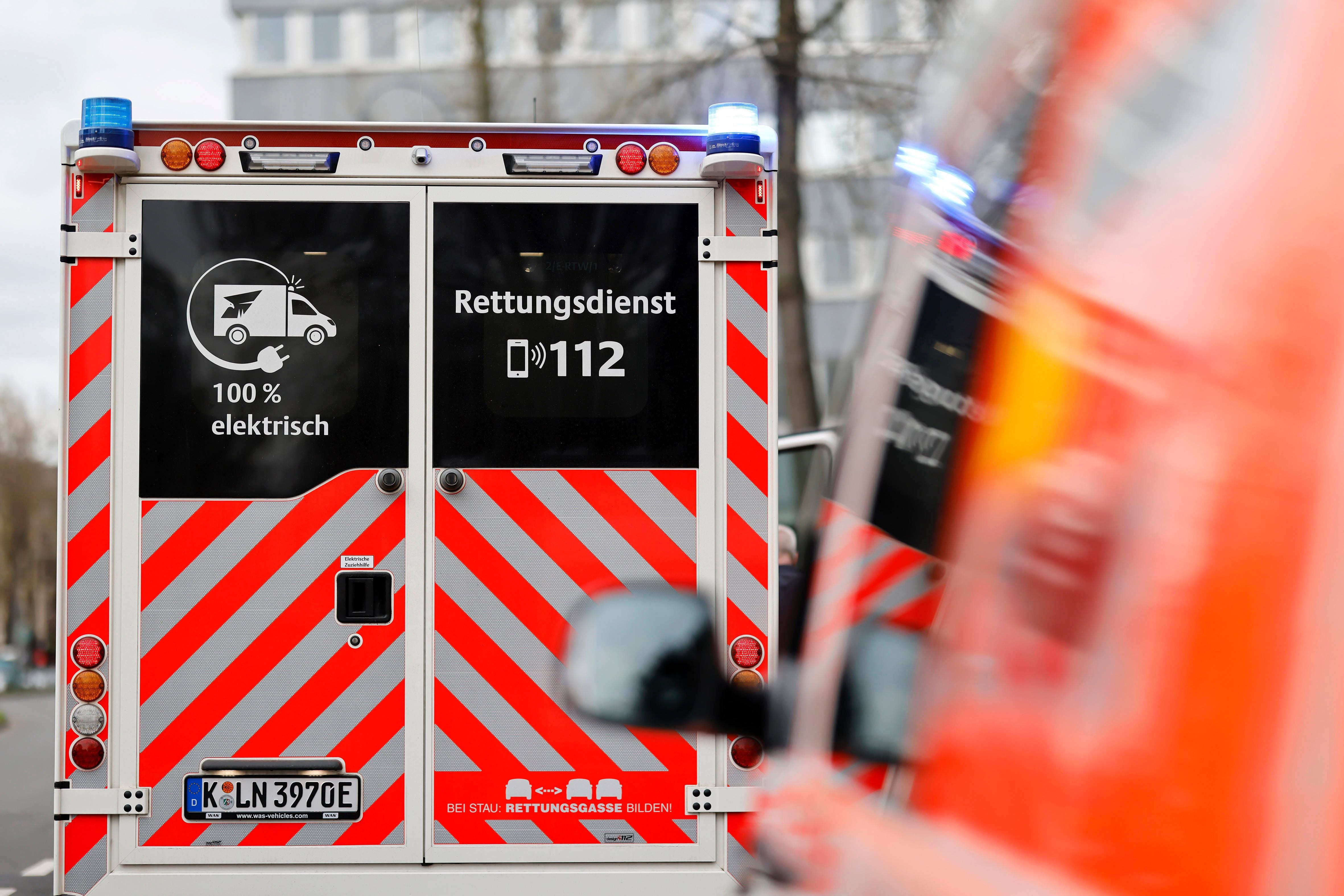 Heckansicht eines elektrischen Rettungswagens mit Blaulicht und Warnstreifen in Köln.