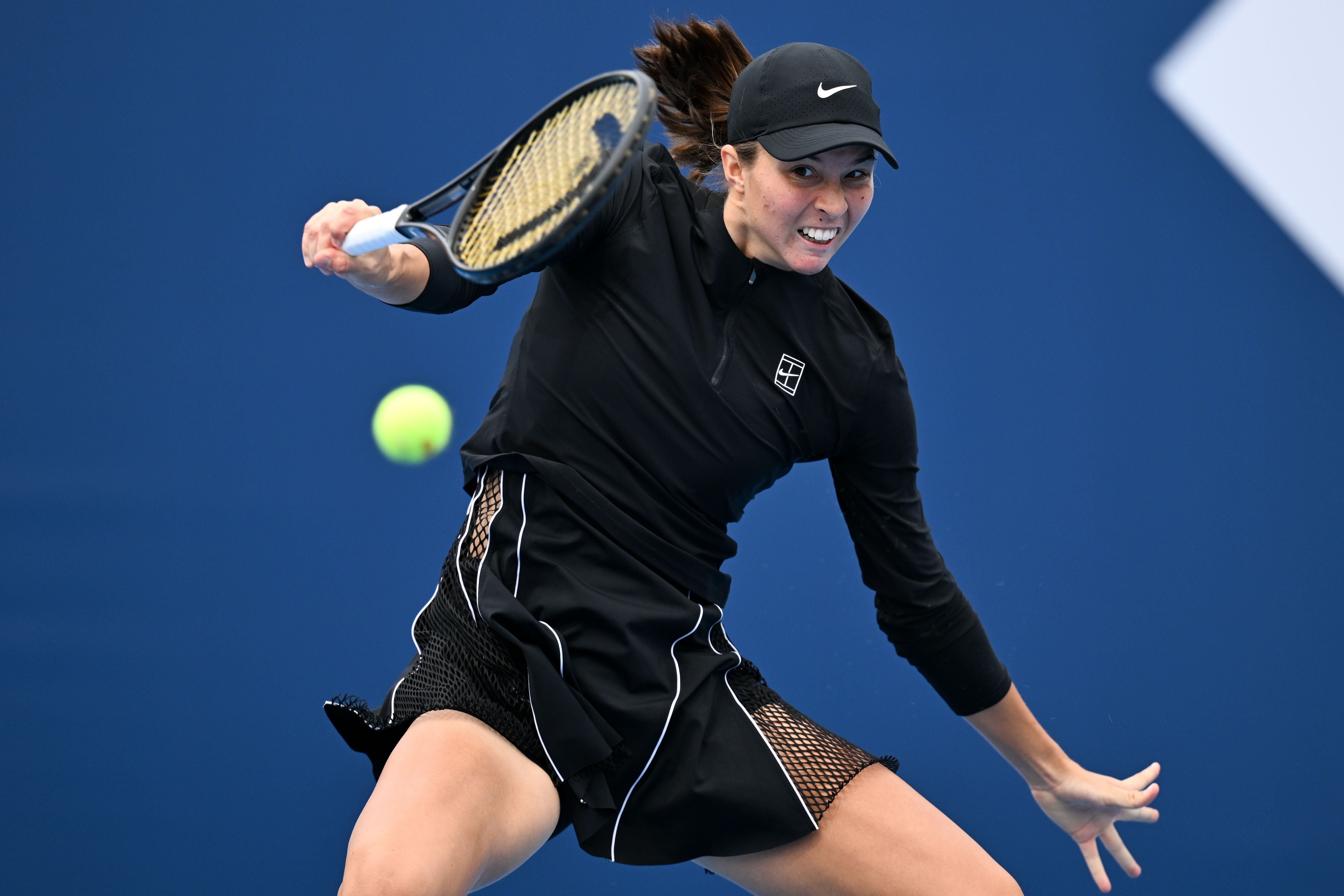 Eine Tennisspielerin schlägt den Ball während eines Matches auf Hartplatz.