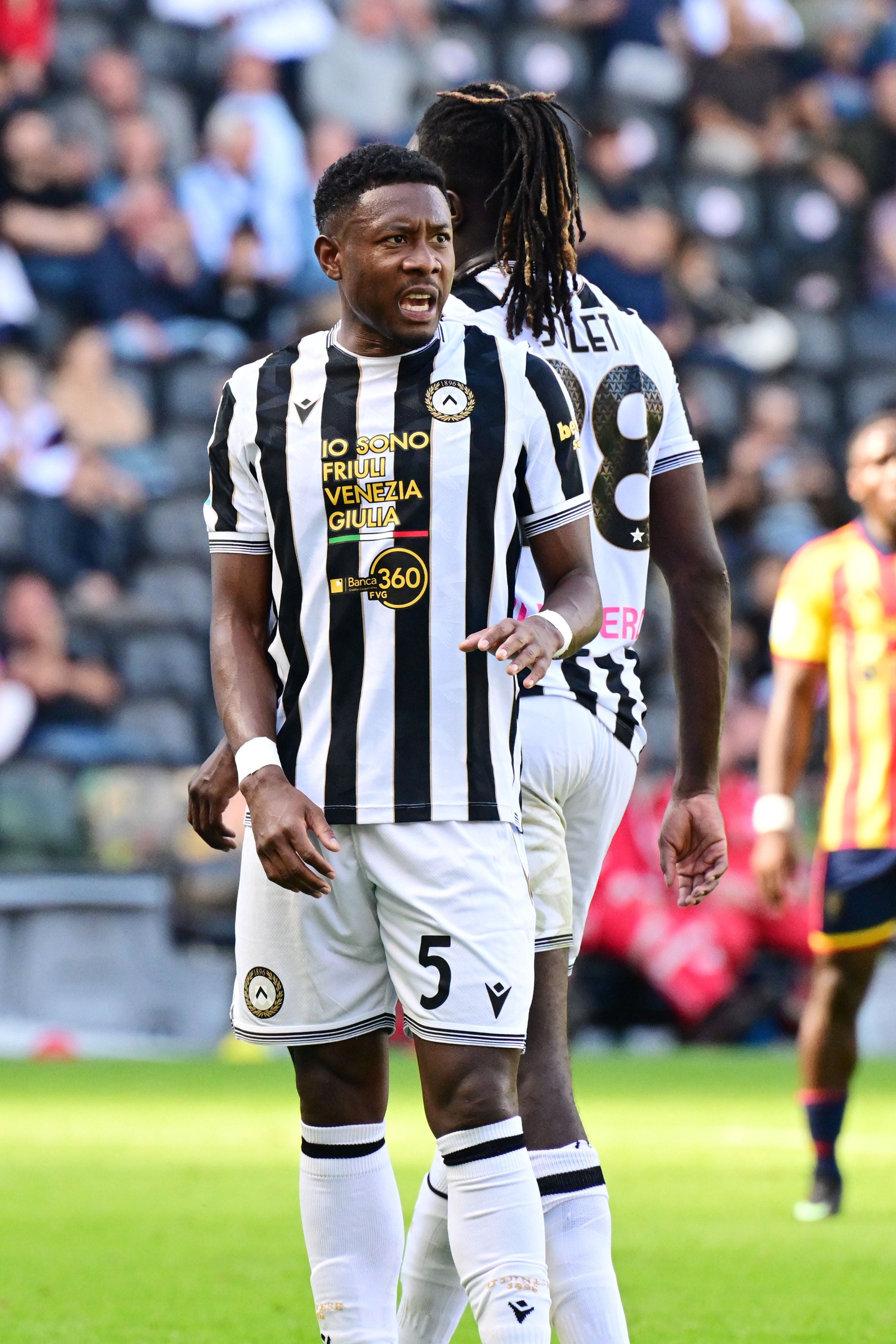 Ein Udinese-Spieler im gestreiften Trikot steht auf dem Spielfeld während eines Fußballspiels.