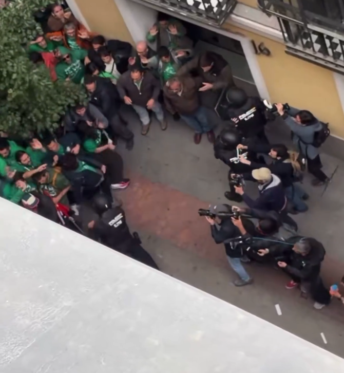 Polizisten räumen eine protestierende Menschenmenge vor einem Gebäude in Madrid, Fotografen dokumentieren.
