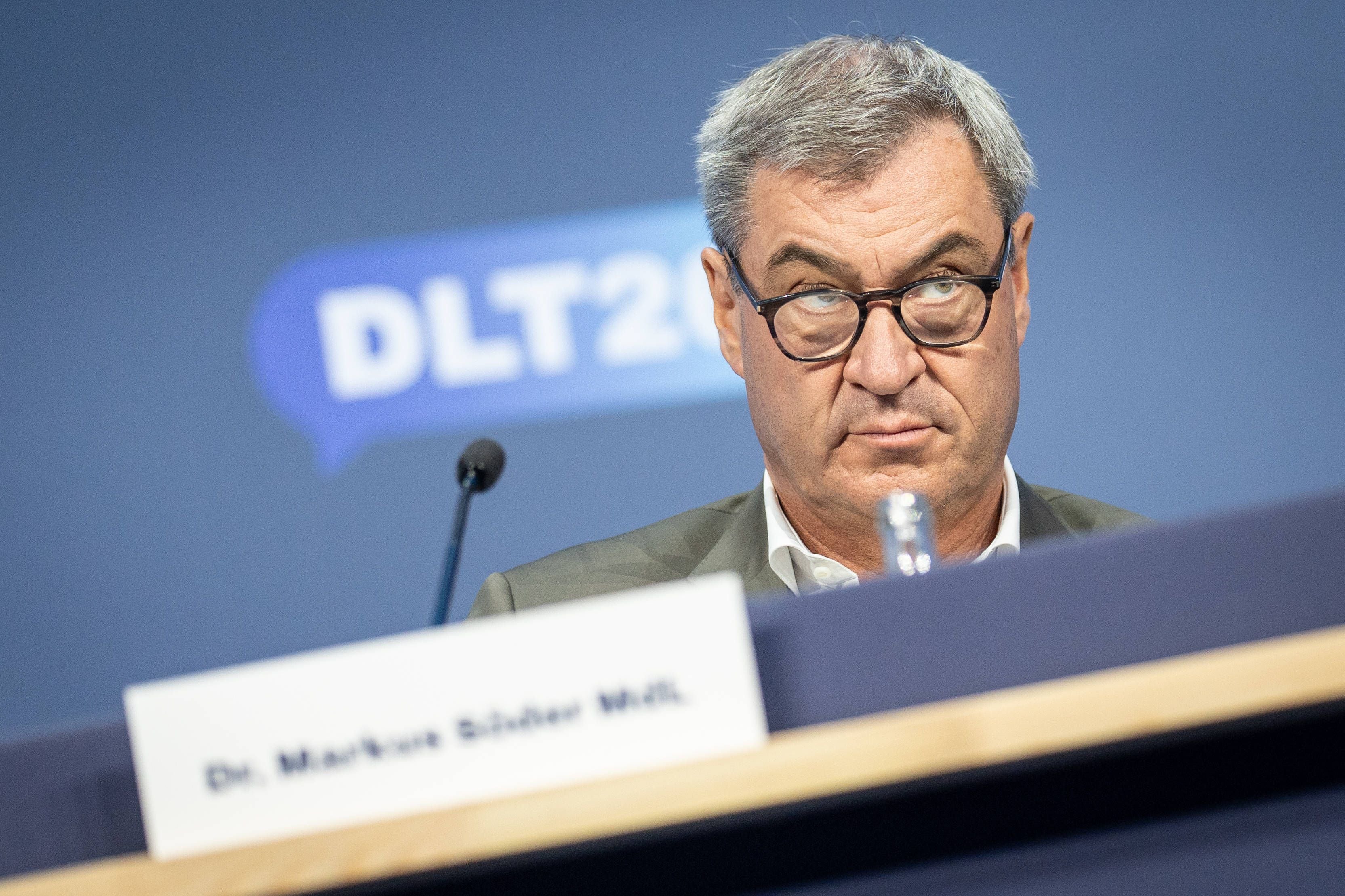 Ein Mann mit Brille sitzt auf einem Podium, im Hintergrund steht "DLT2026".