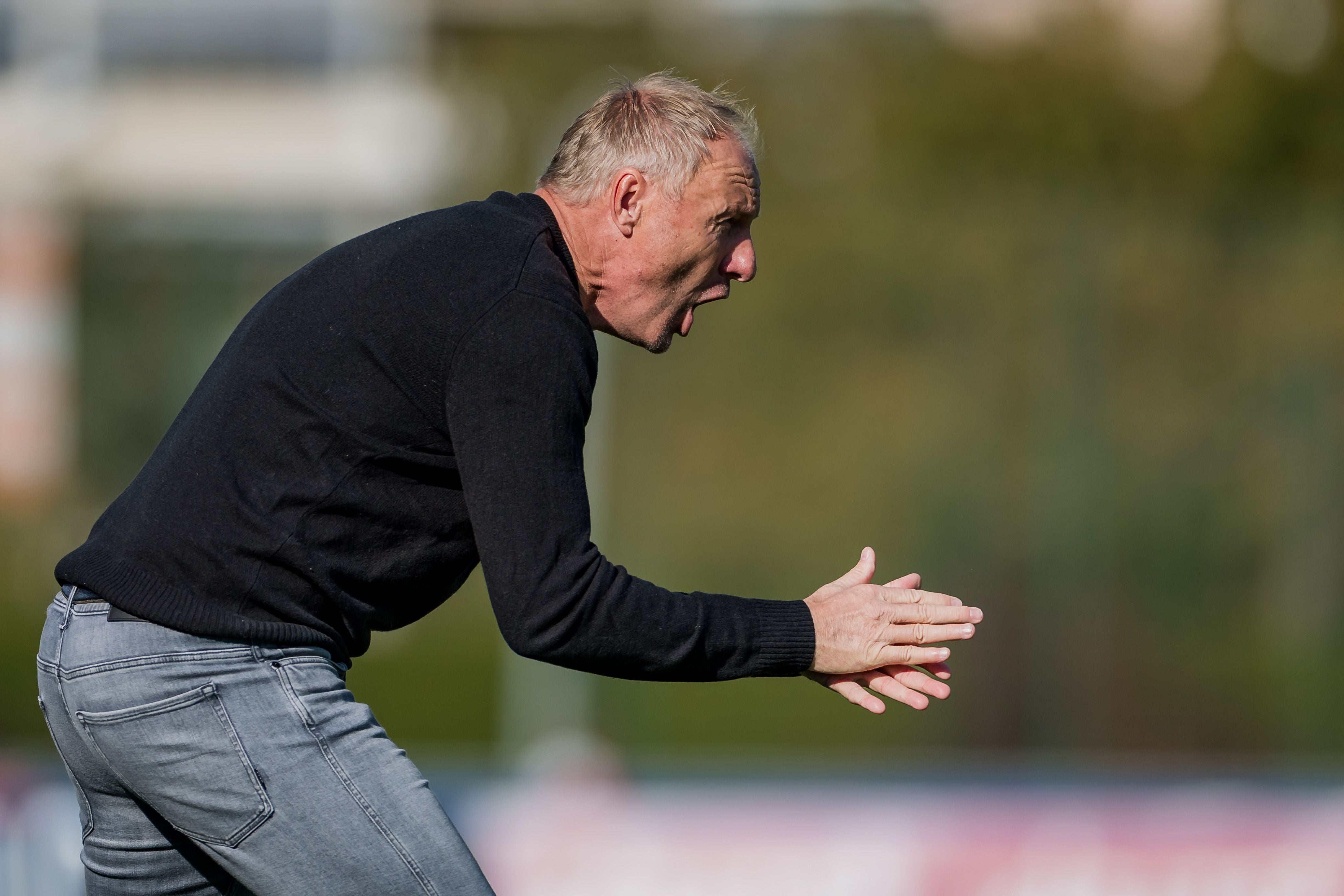 Ein Fußballtrainer klatscht an der Seitenlinie und ruft Anweisungen aufs Spielfeld.
