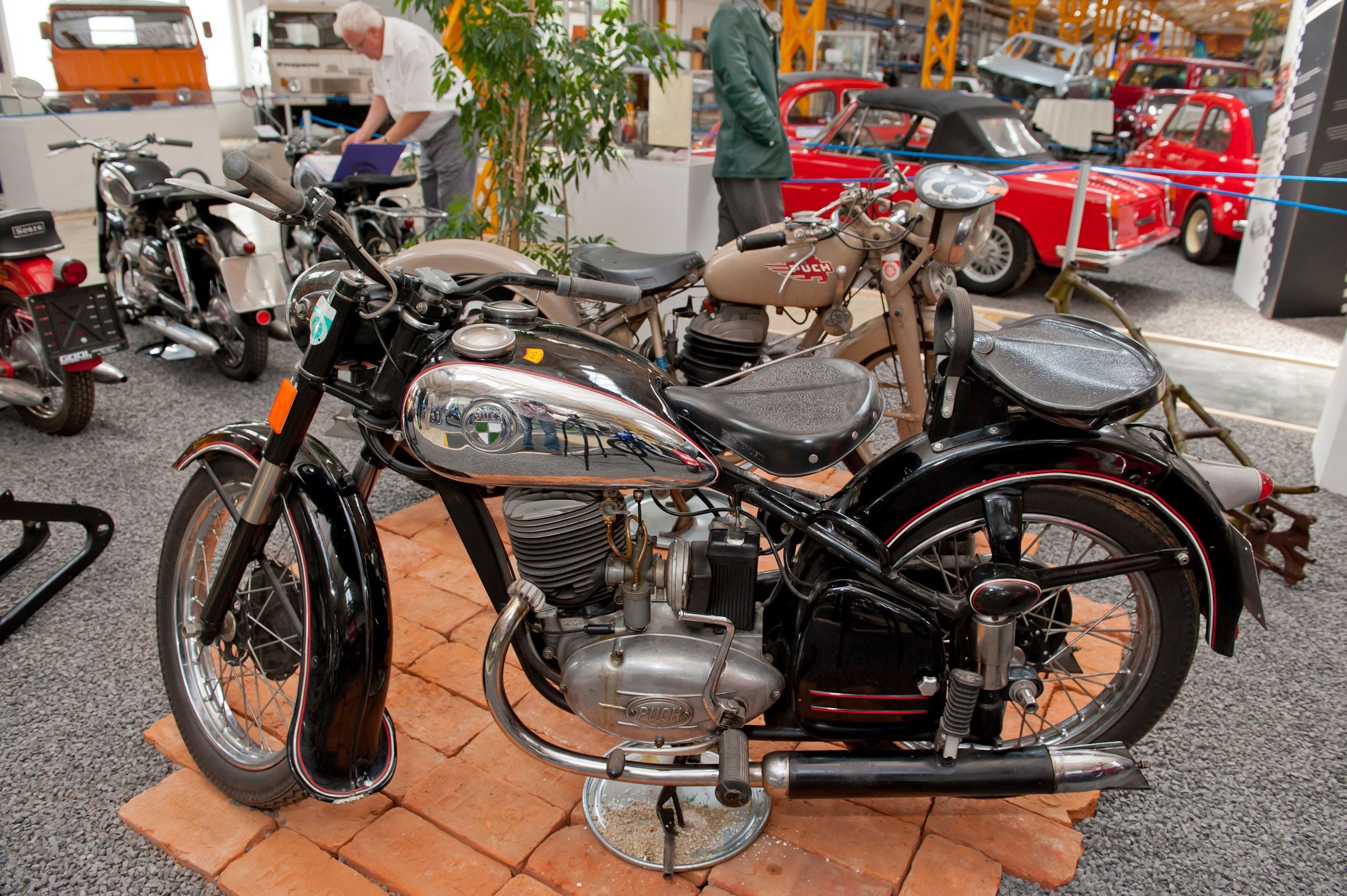 Ausstellung historischer Autos im Puch-Museum mit alten Fahrzeugen und großformatigen Bildern.