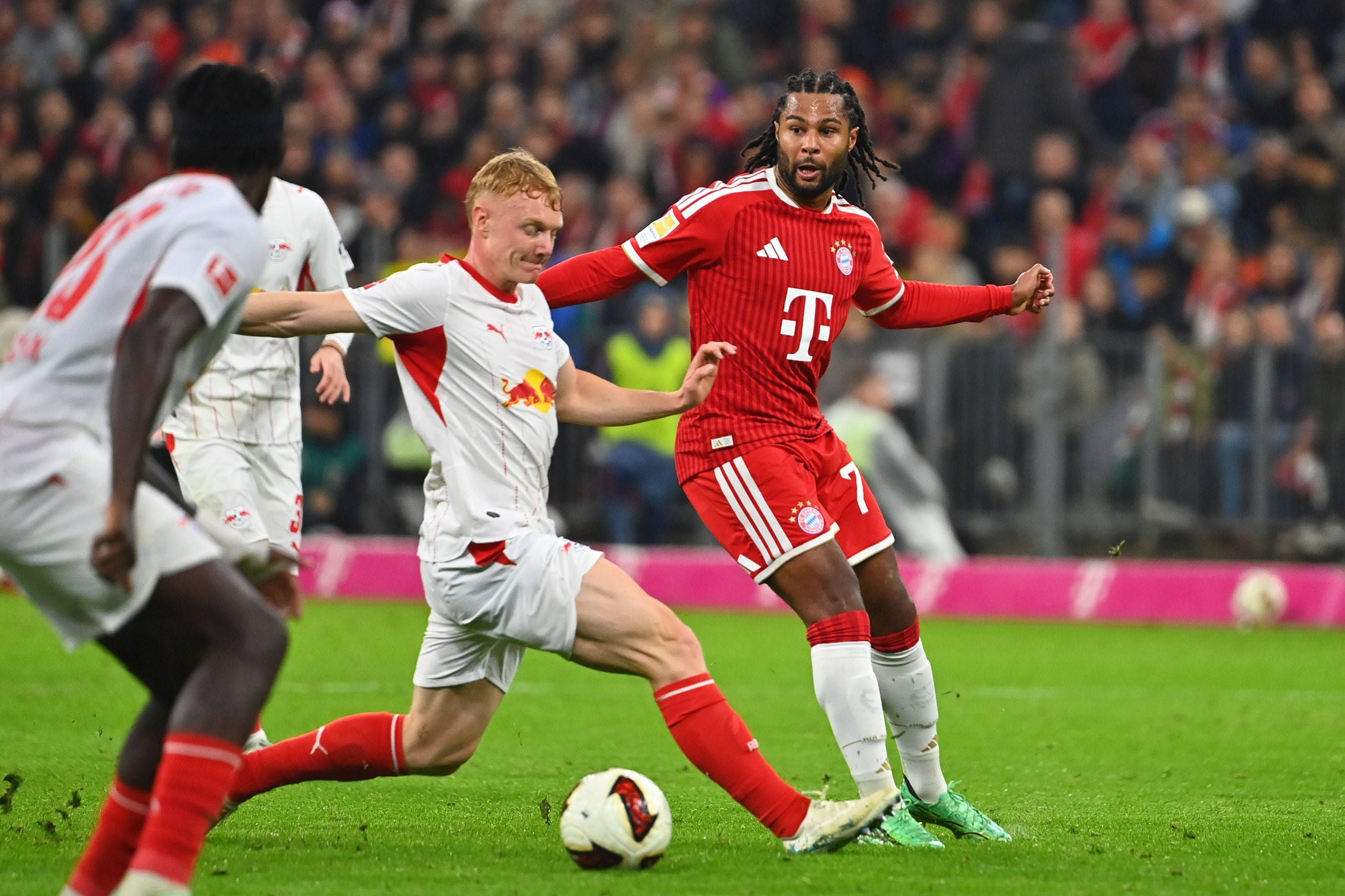 Ein Spieler von Bayern München und ein Spieler von RB Leipzig kämpfen im Stadion um den Ball.