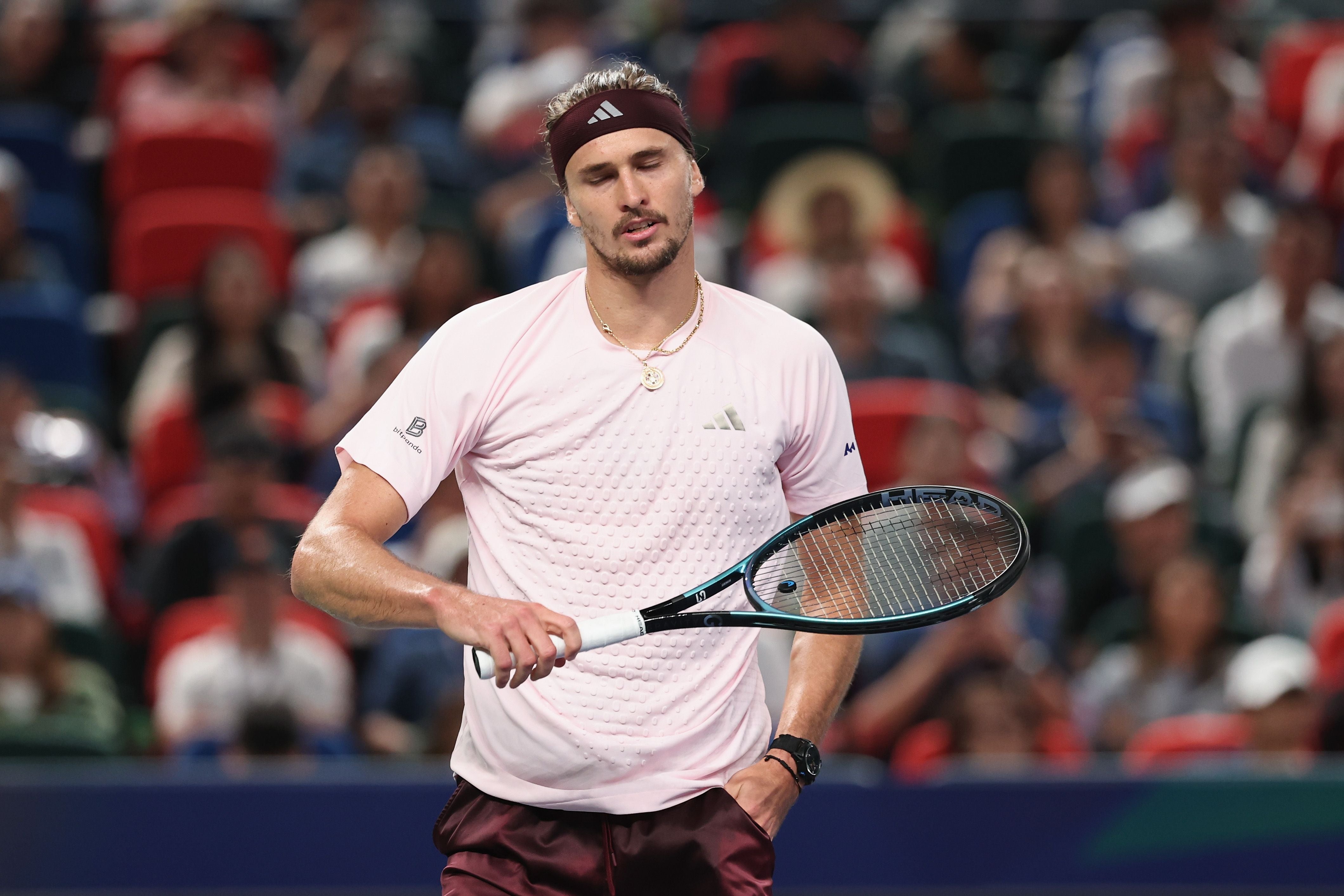 Ein Tennisspieler mit Stirnband und Schläger wirkt enttäuscht während eines Matches.