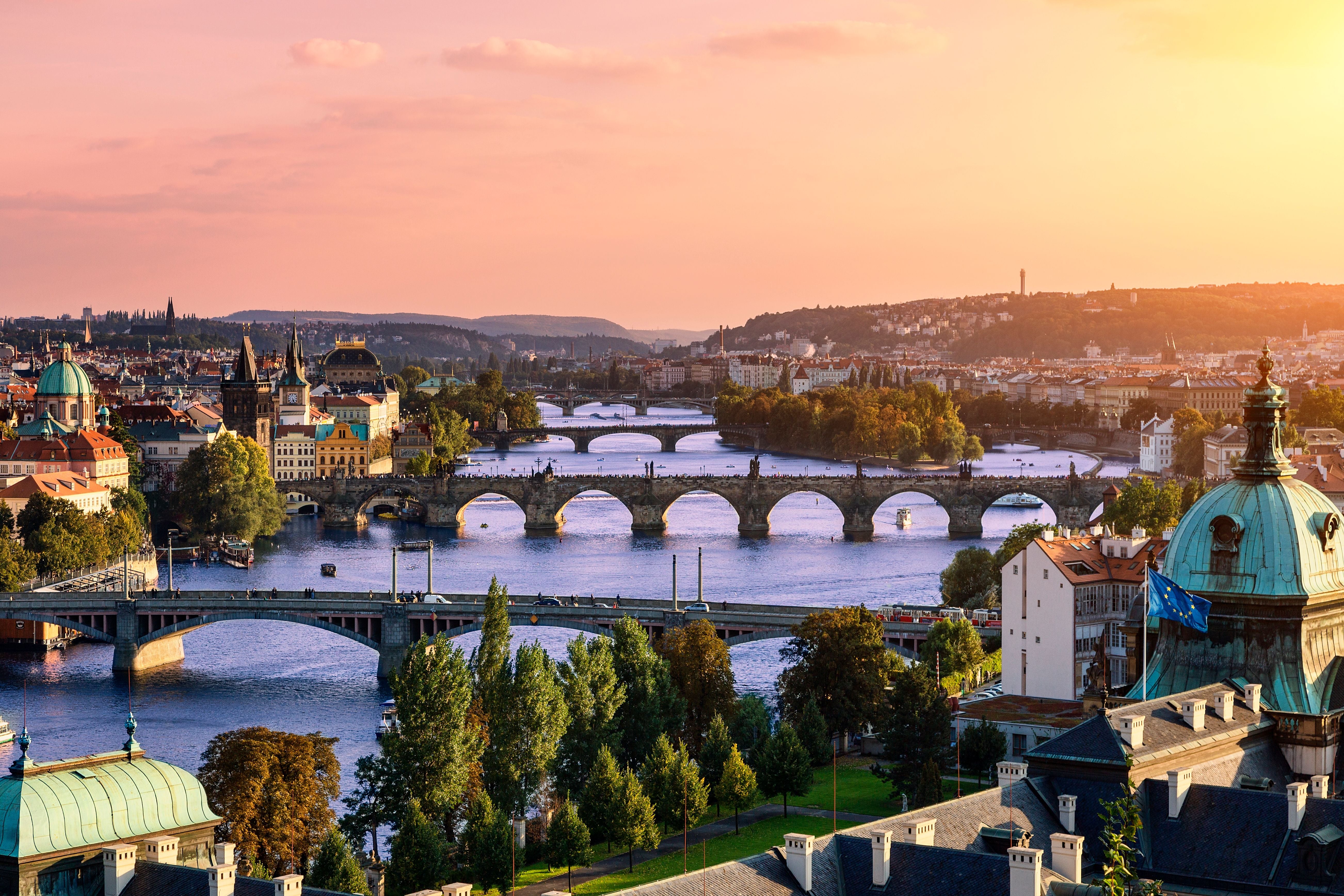 Blick auf die Moldau und mehrere Brücken in Prag bei Sonnenuntergang.
