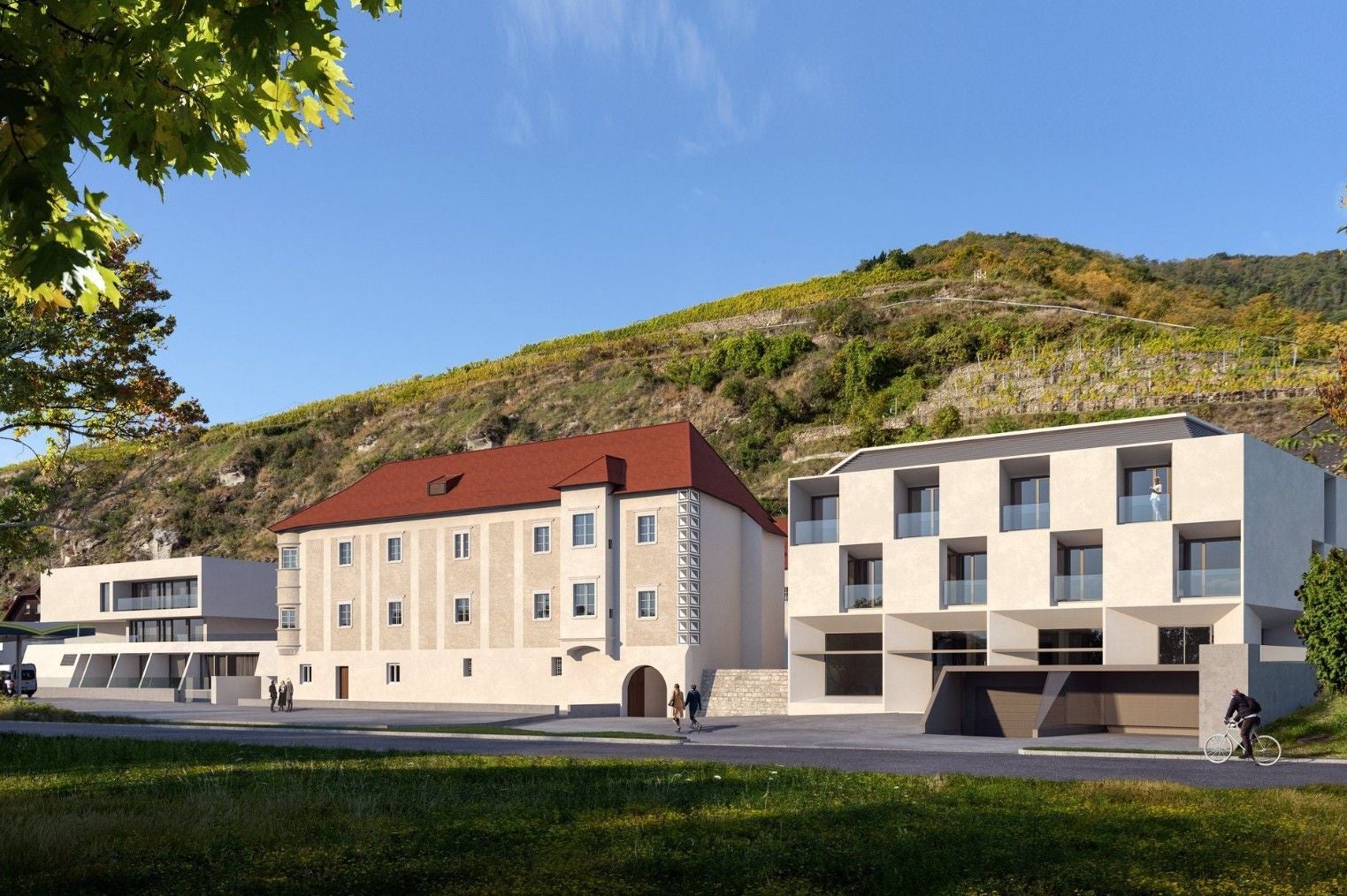 Moderne und historische Gebäude vor einem bewaldeten Hügel am Förthof bei sonnigem Wetter.