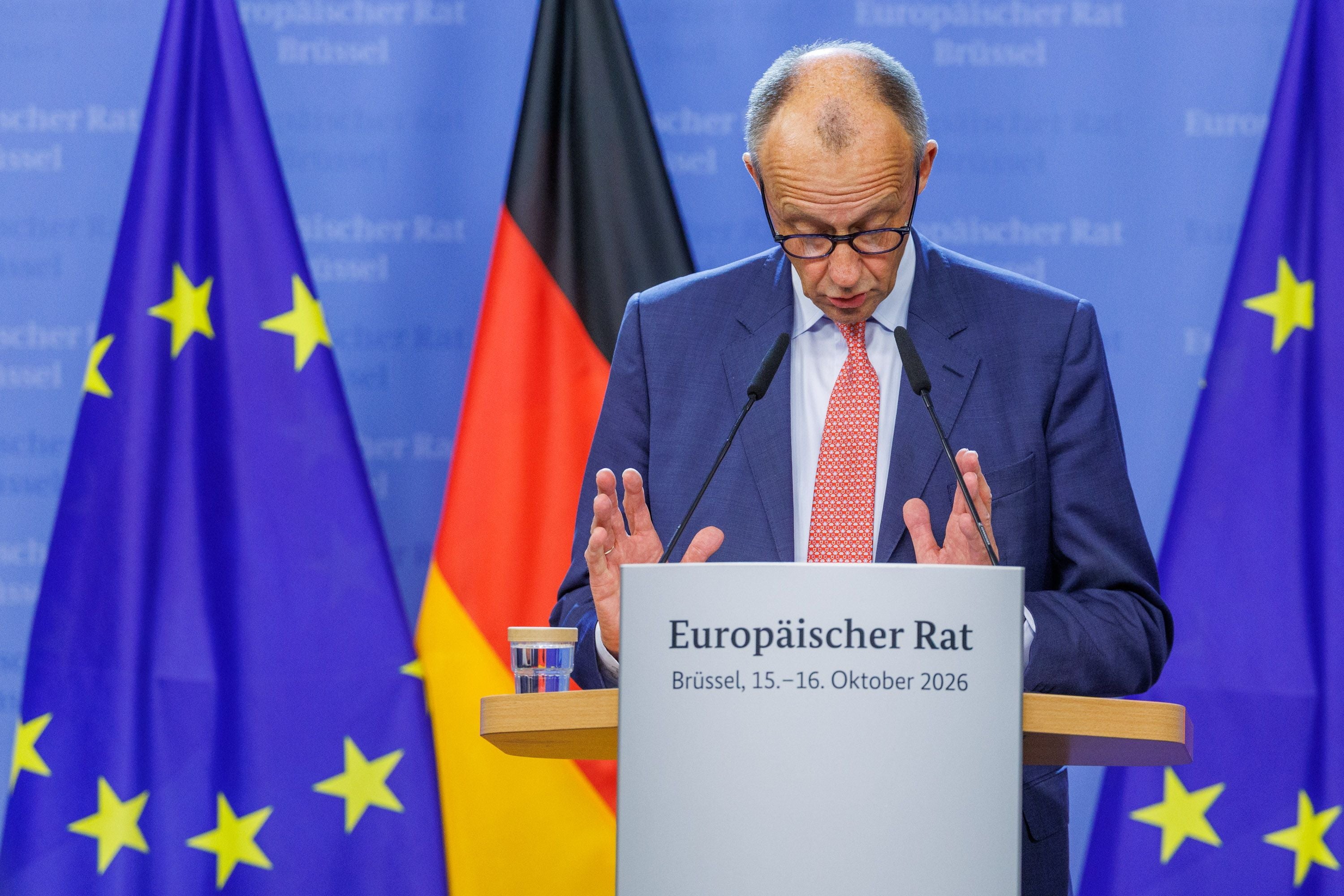 Ein Mann spricht auf einer Pressekonferenz vor EU- und Deutschlandfahnen in Brüssel.
