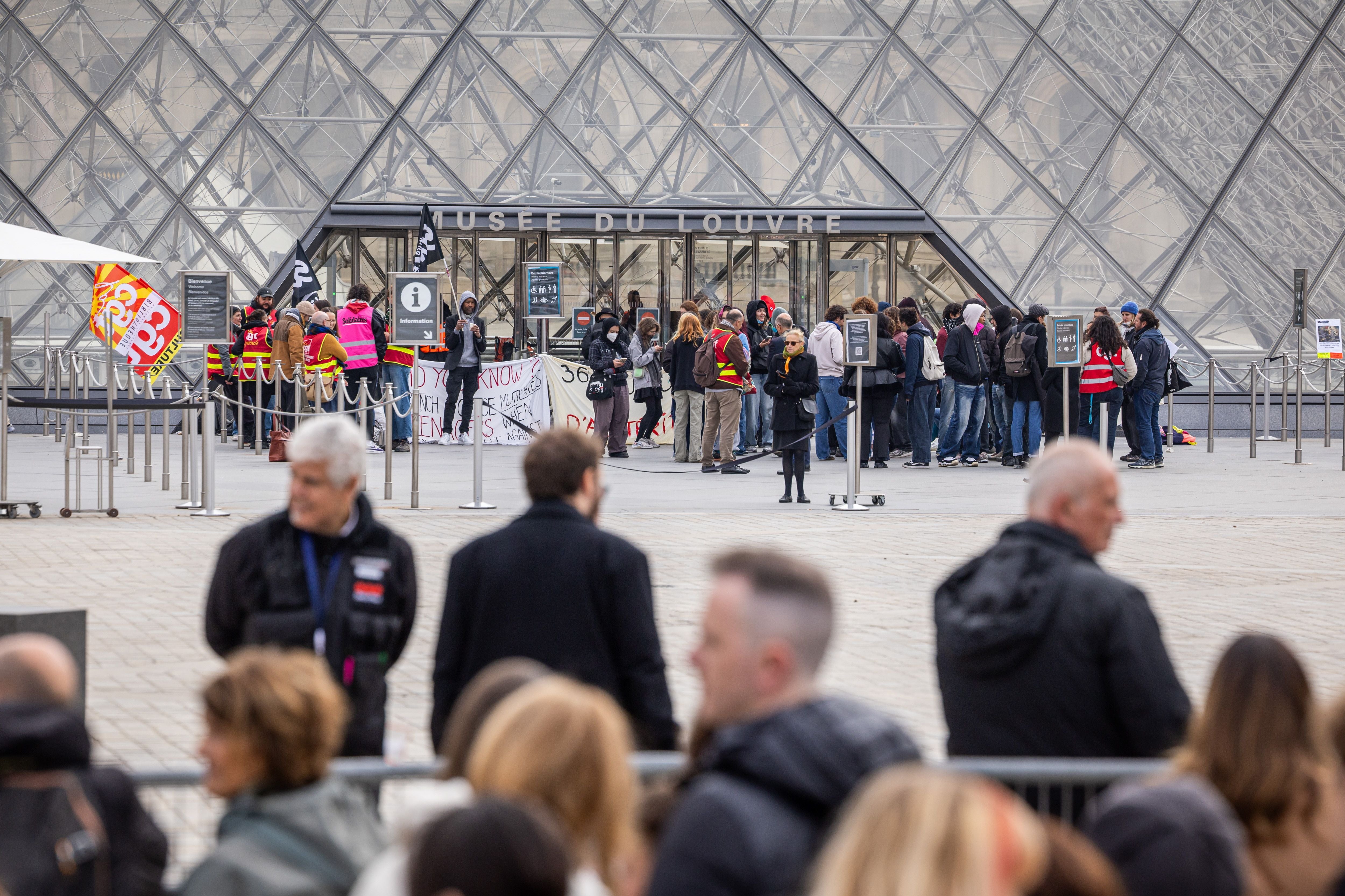 Demonstranten blockieren den Eingang des Louvre, während Besucher draußen warten.