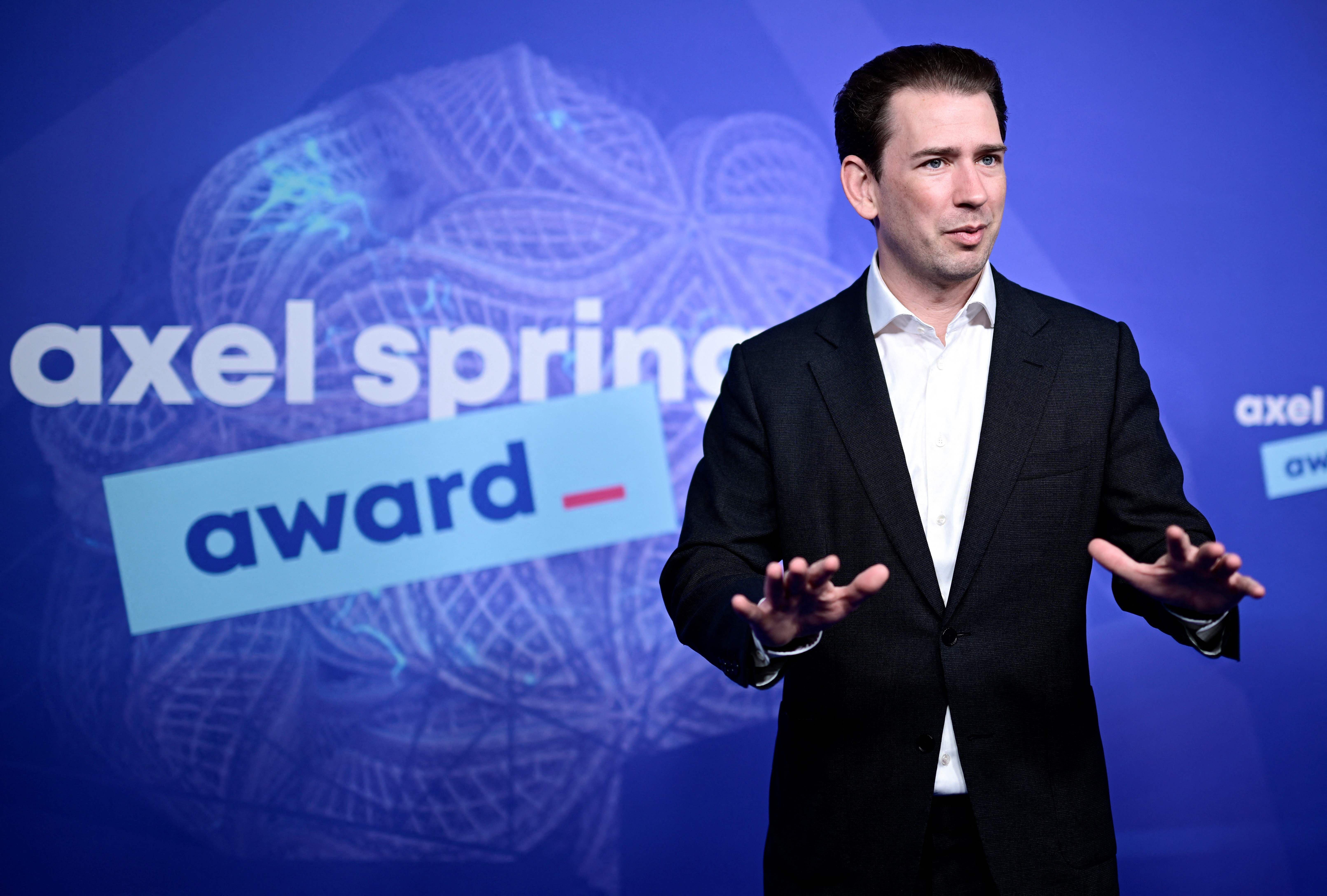 Ein Mann im Anzug steht vor einer Wand mit dem Axel-Springer-Award-Logo in Berlin.