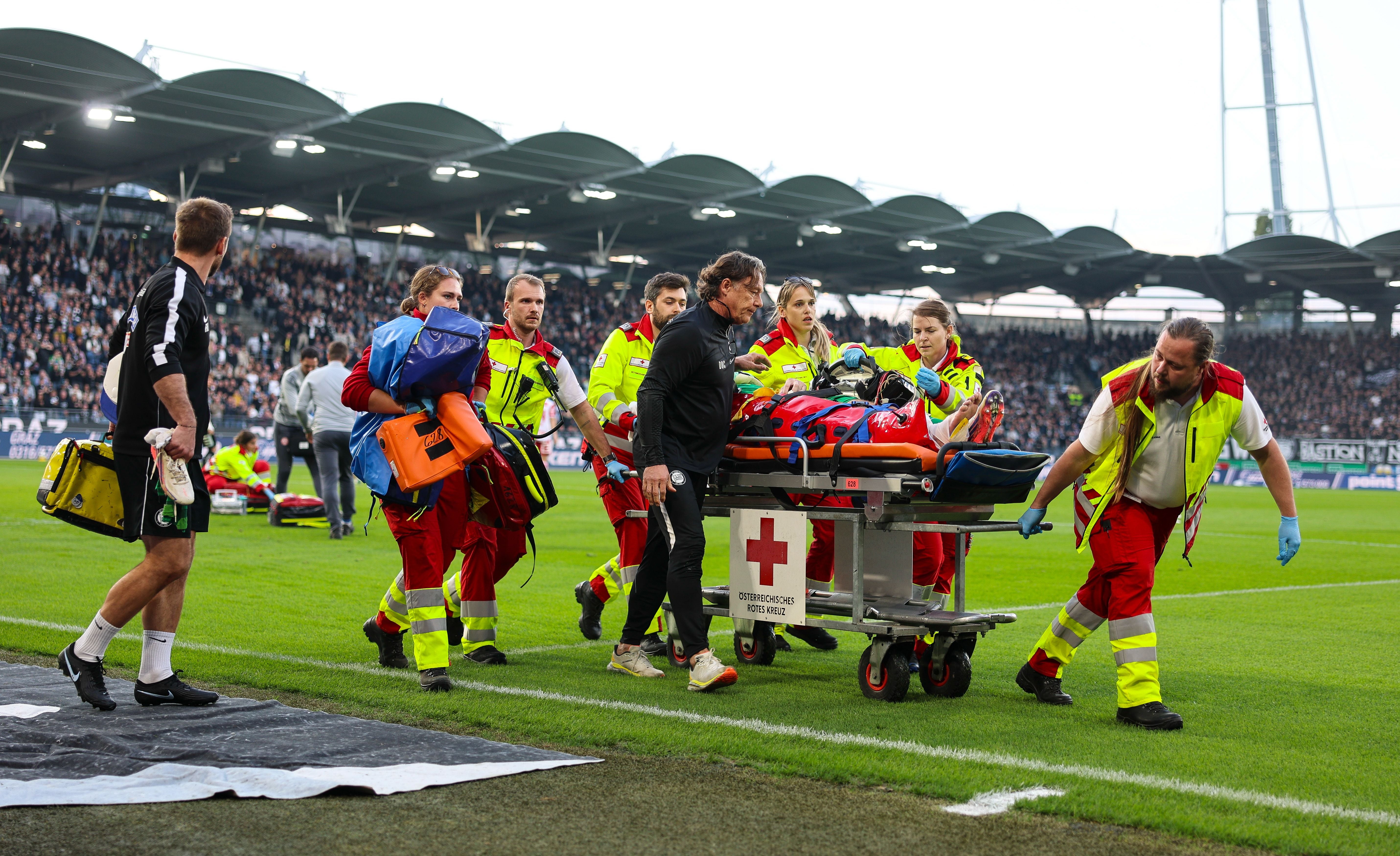 Sanitäter bringen einen verletzten Fußballspieler auf einer Trage vom Spielfeld.