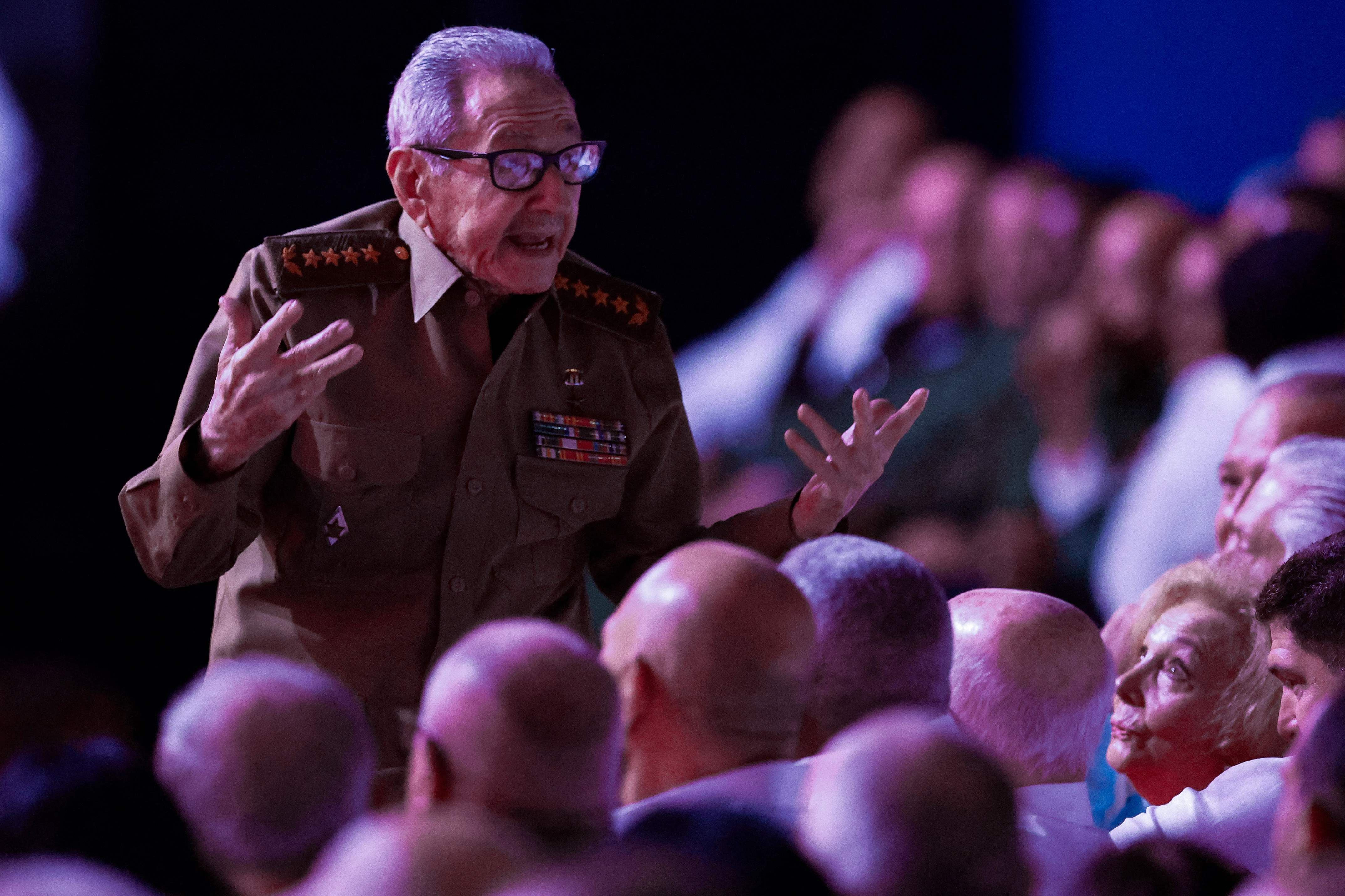 Ein älterer Mann in Militäruniform spricht gestikulierend vor einem Publikum in einem Theater.