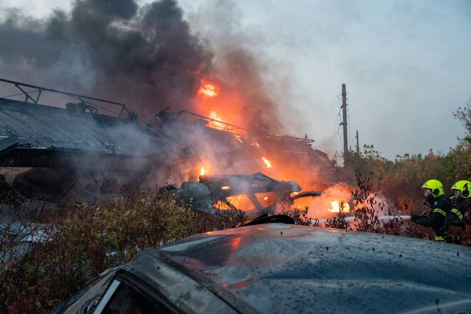 Feuerwehrleute löschen brennende Autowracks nach einem Güterzugunfall bei Schwechat.