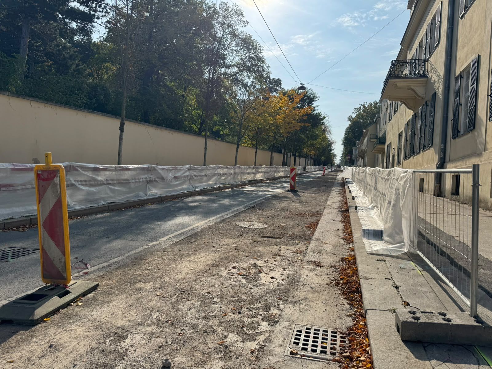 Straße mit Absperrungen und Warnschildern wegen Asbest-Sanierung, Gehweg teils abgedeckt.