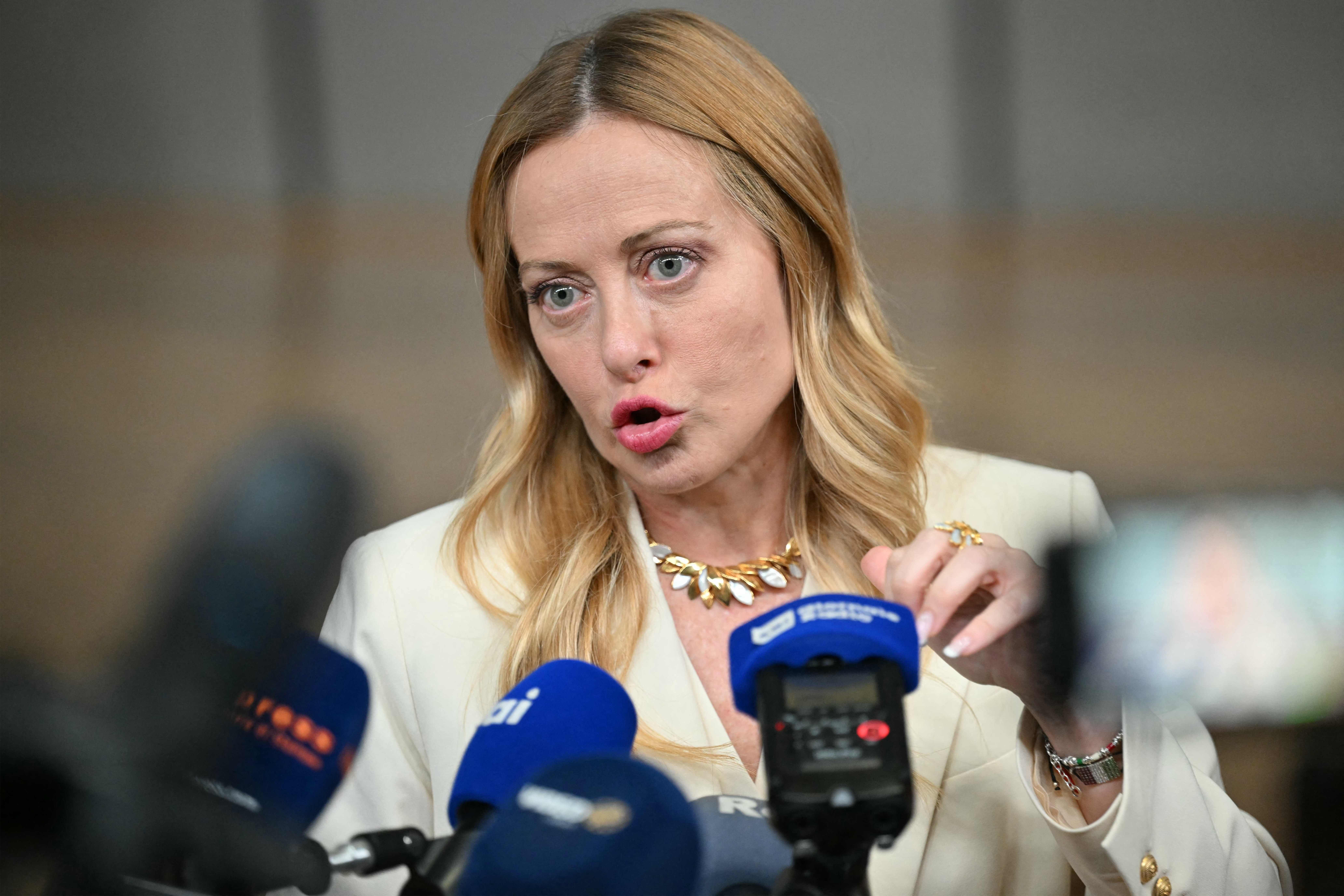 Eine Frau spricht vor mehreren Mikrofonen auf einer Pressekonferenz.