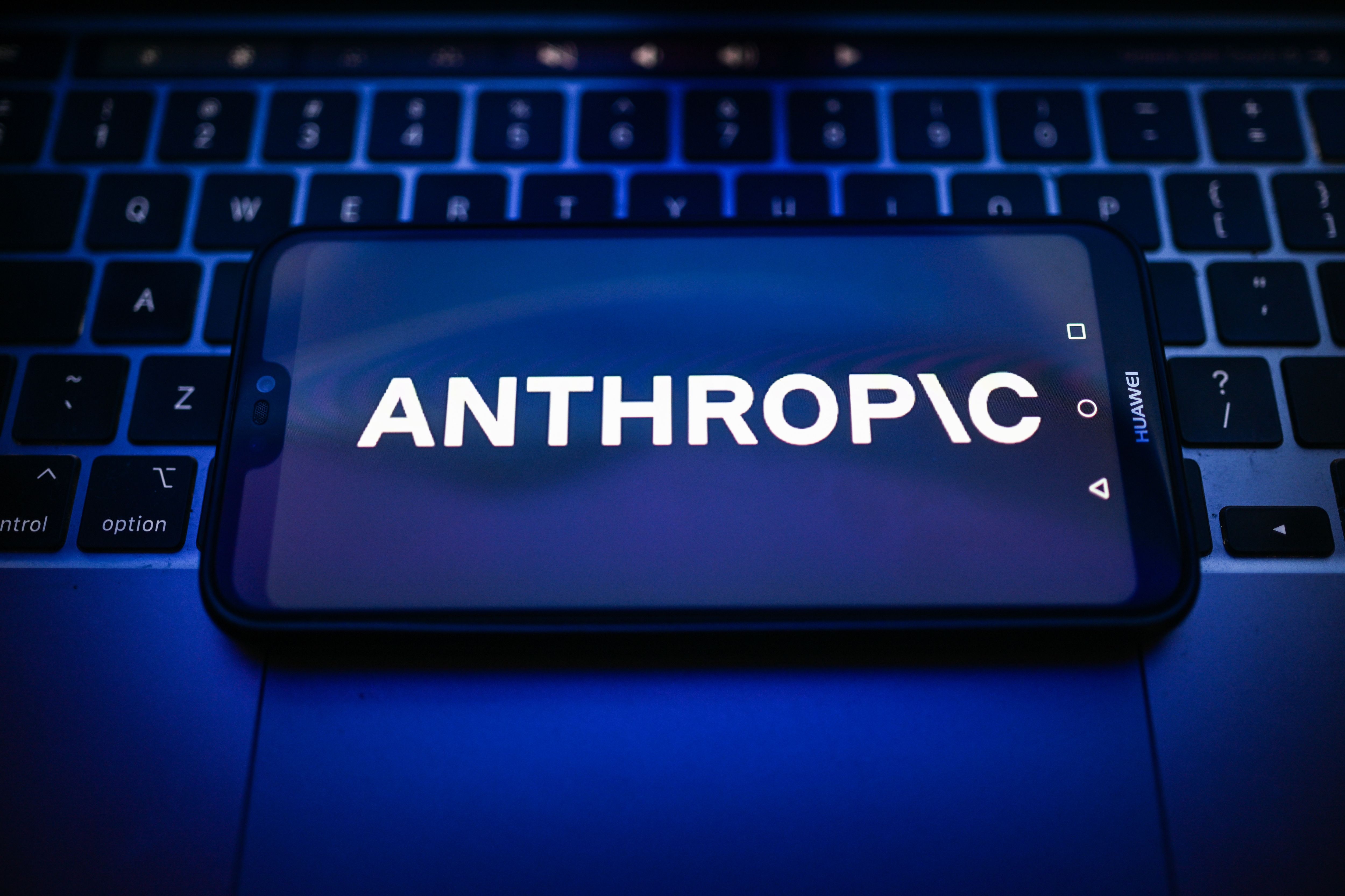 Ein Smartphone mit dem Anthropic-Logo liegt auf einer Laptop-Tastatur.