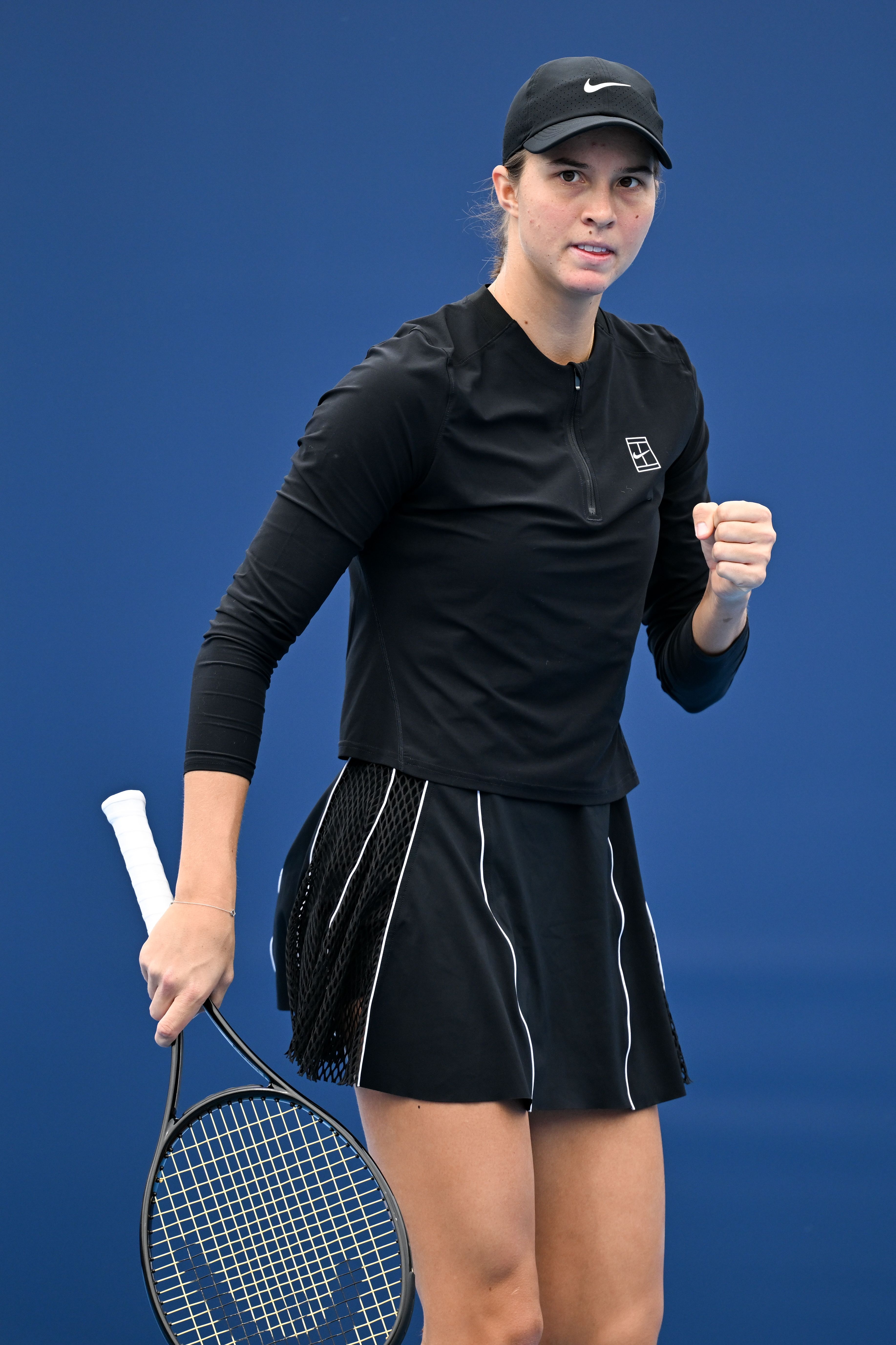 Eine Tennisspielerin in schwarzer Kleidung ballt die Faust auf dem Platz.