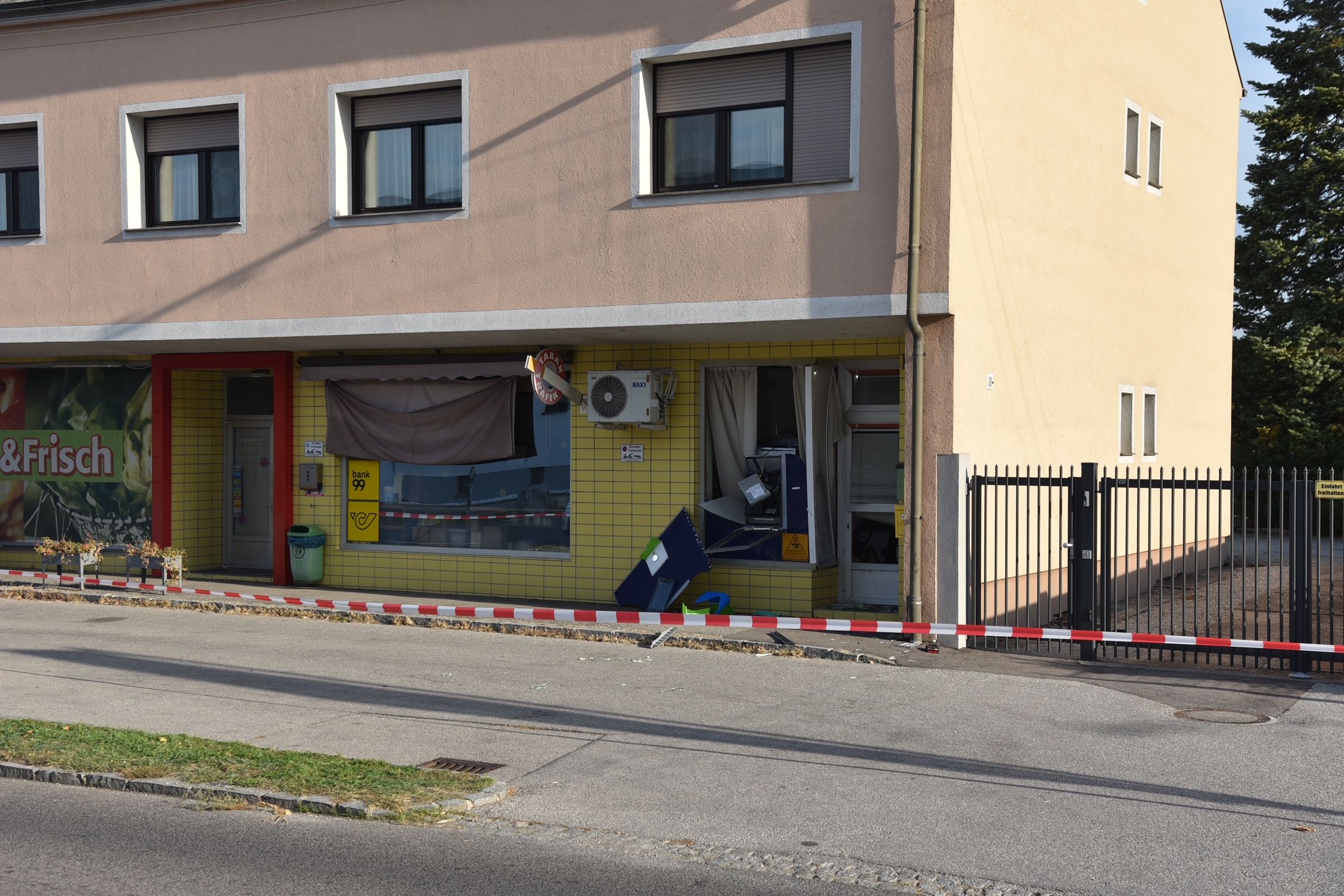 Ein beschädigter Bankautomat in einem Gebäude, abgesperrt mit rot-weißem Band.