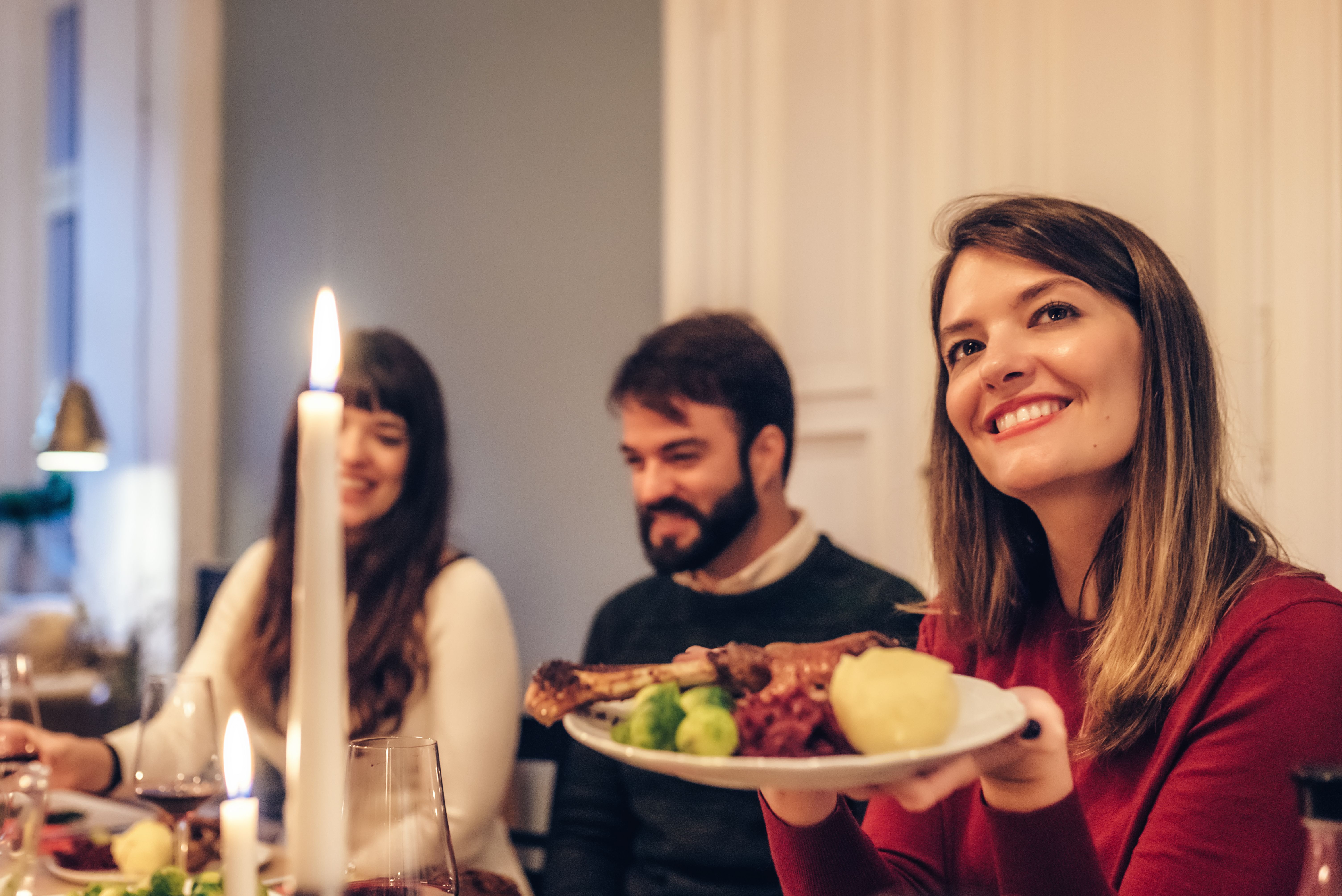 Junge Menschen essen bei Kerzenschein ein traditionelles deutsches Weihnachtsessen.
