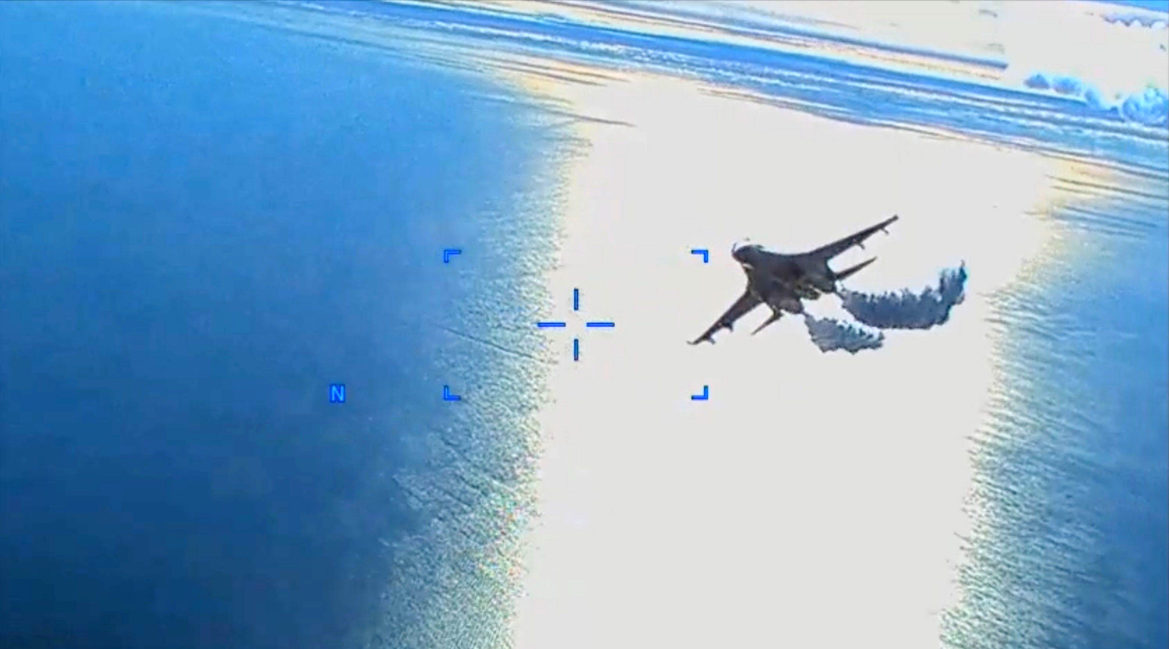 Ein Kampfjet fliegt über das Meer und hinterlässt eine deutliche Rauch- oder Kondensspur.