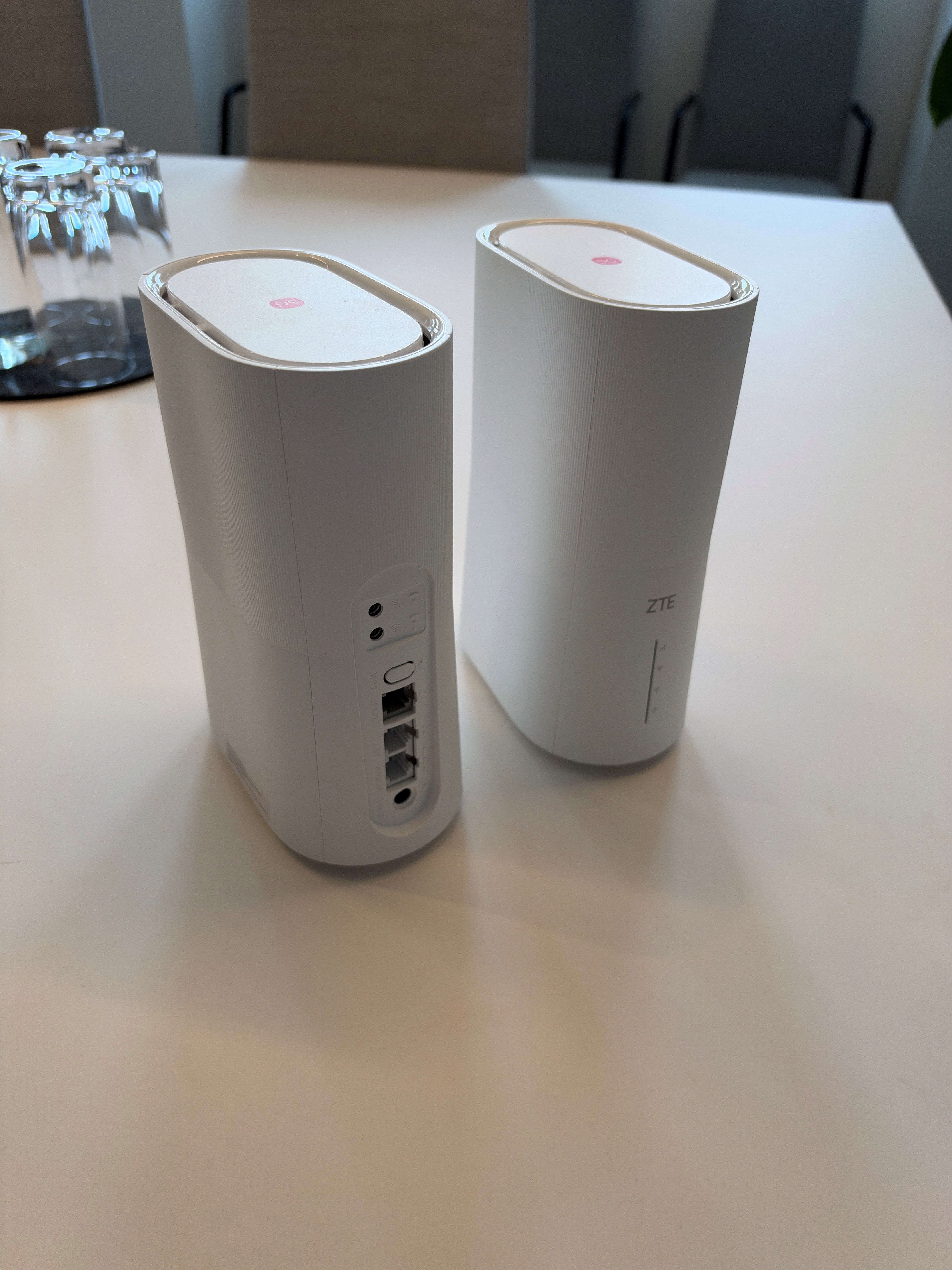 Zwei weiße ZTE-Router stehen auf einem Tisch in einem Konferenzraum.