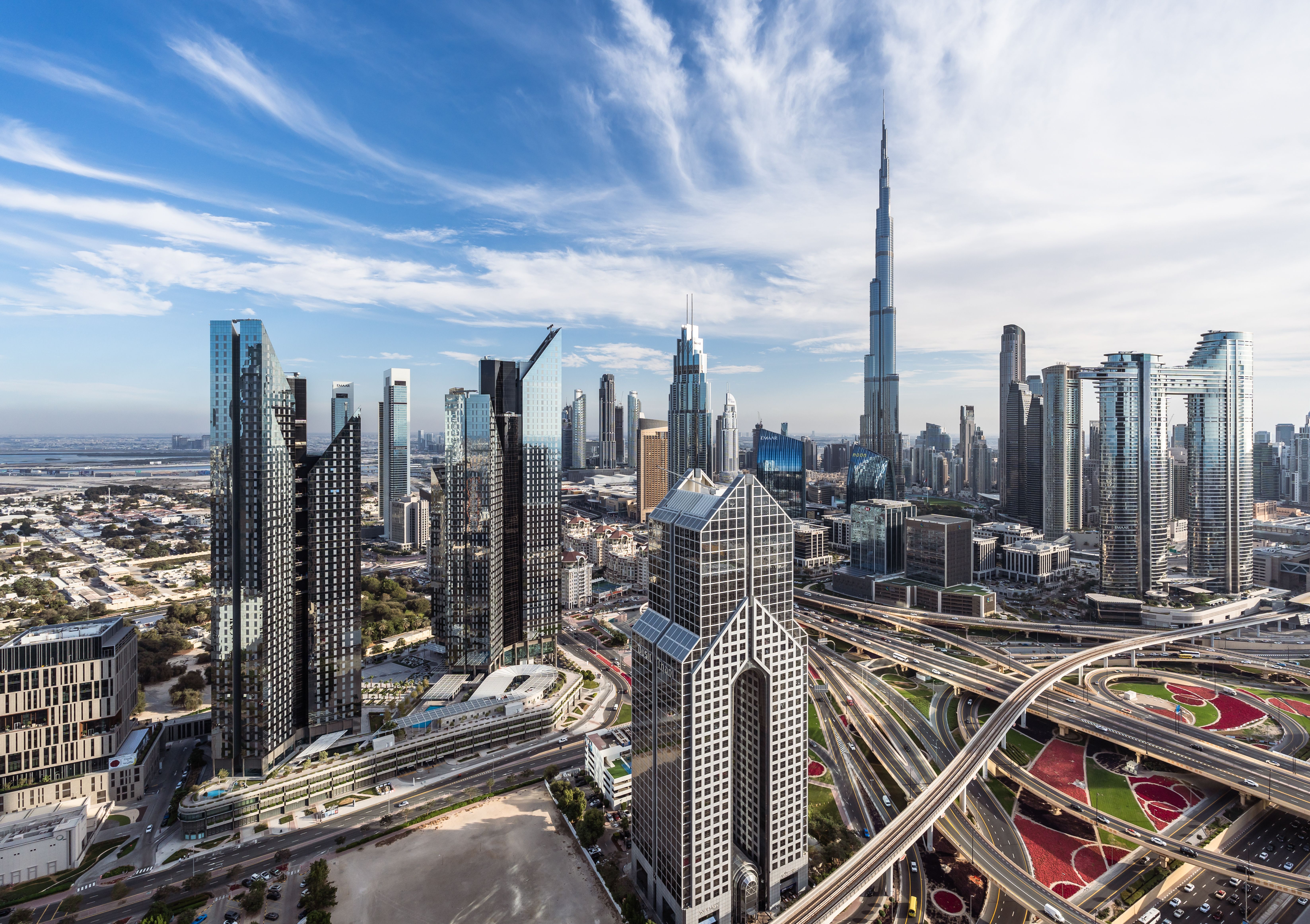 Panorama von Dubais Skyline mit Burj Khalifa, modernen Hochhäusern und breiten Autobahnen im Vordergrund.