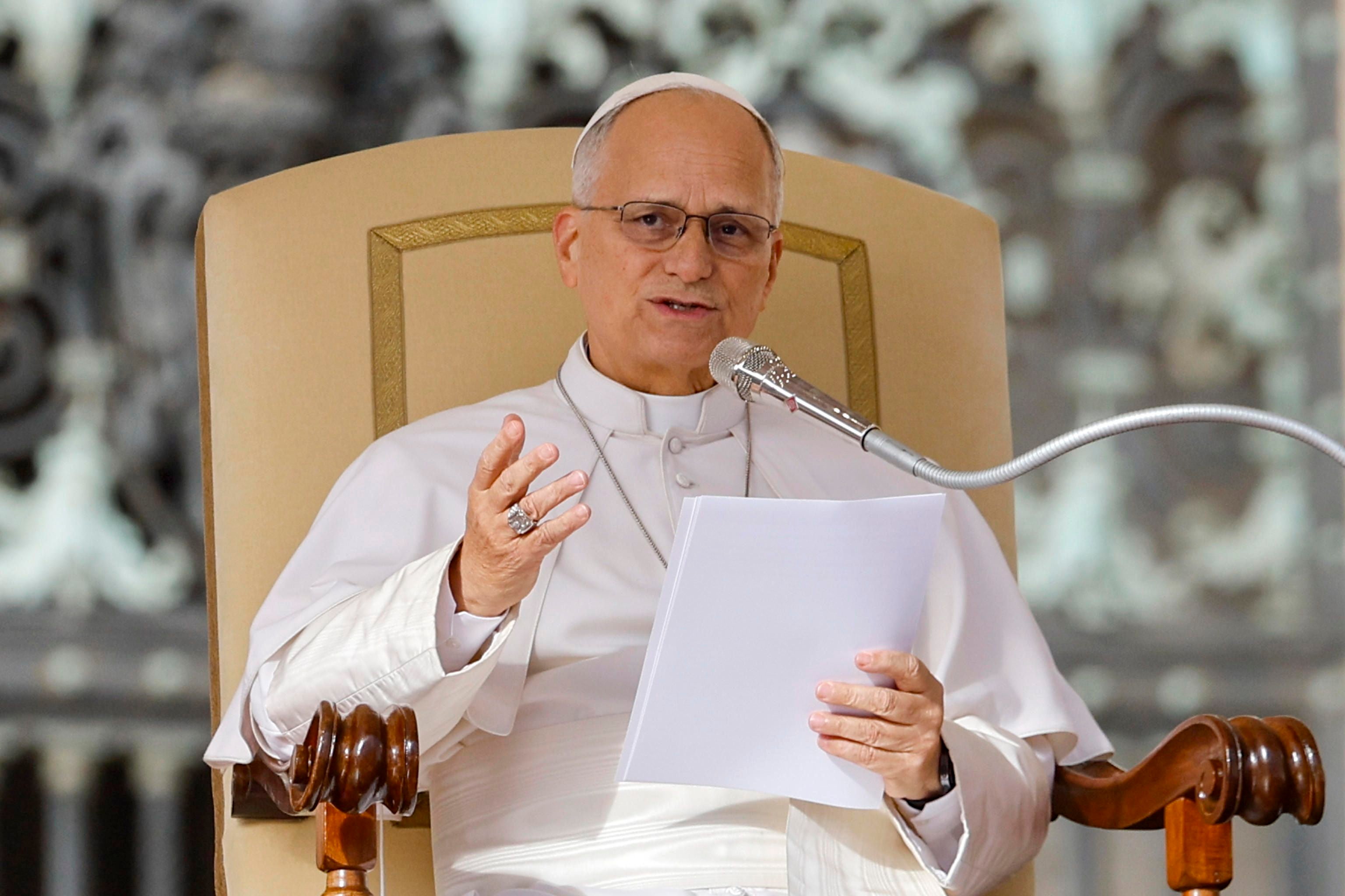 Papst Leo XIV. hält eine Ansprache und liest von Blättern, im Vatikan sitzend.