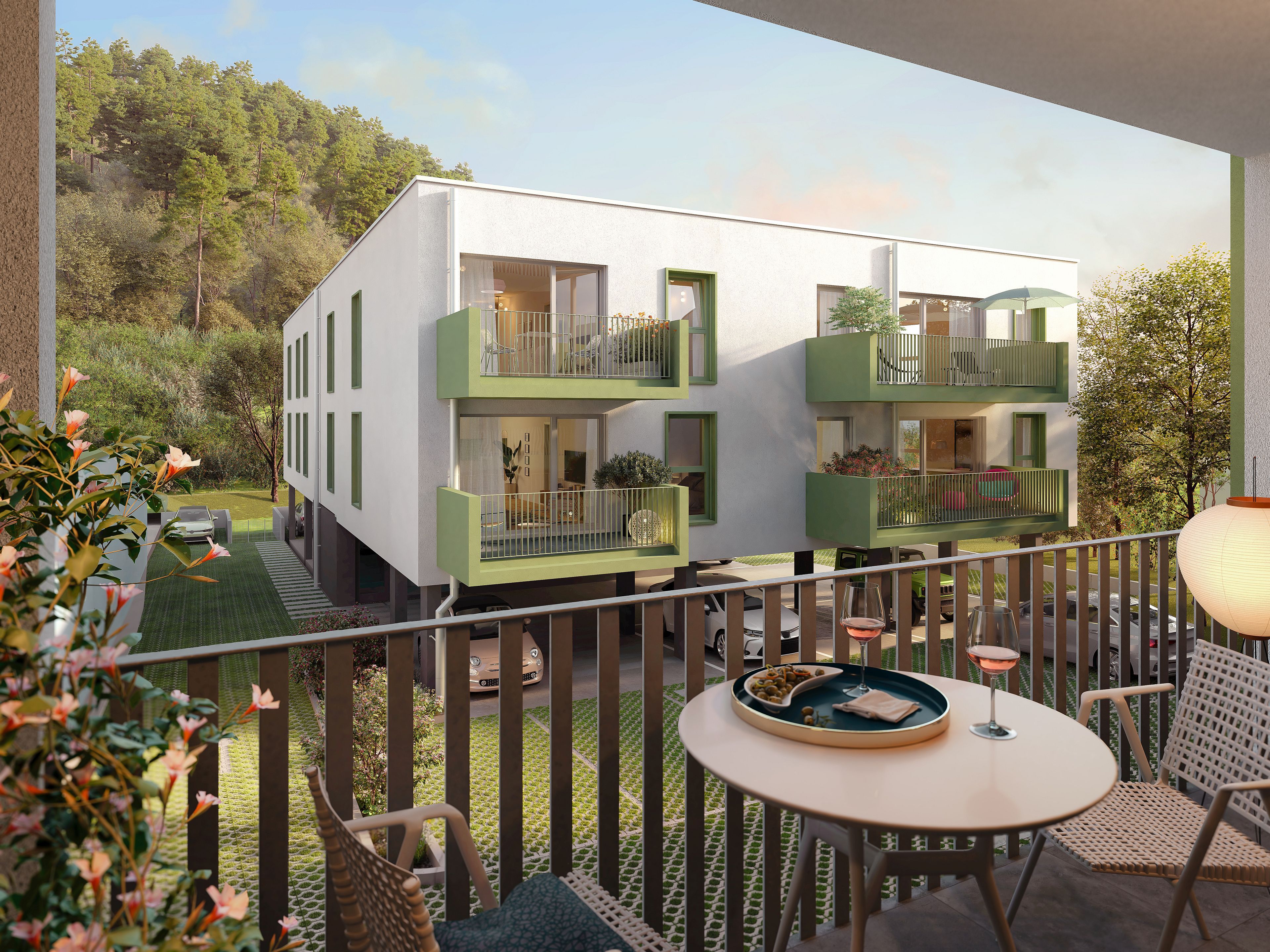 Blick von einem Balkon auf moderne Wohnhäuser mit grünen Balkonen und umgebender Natur.