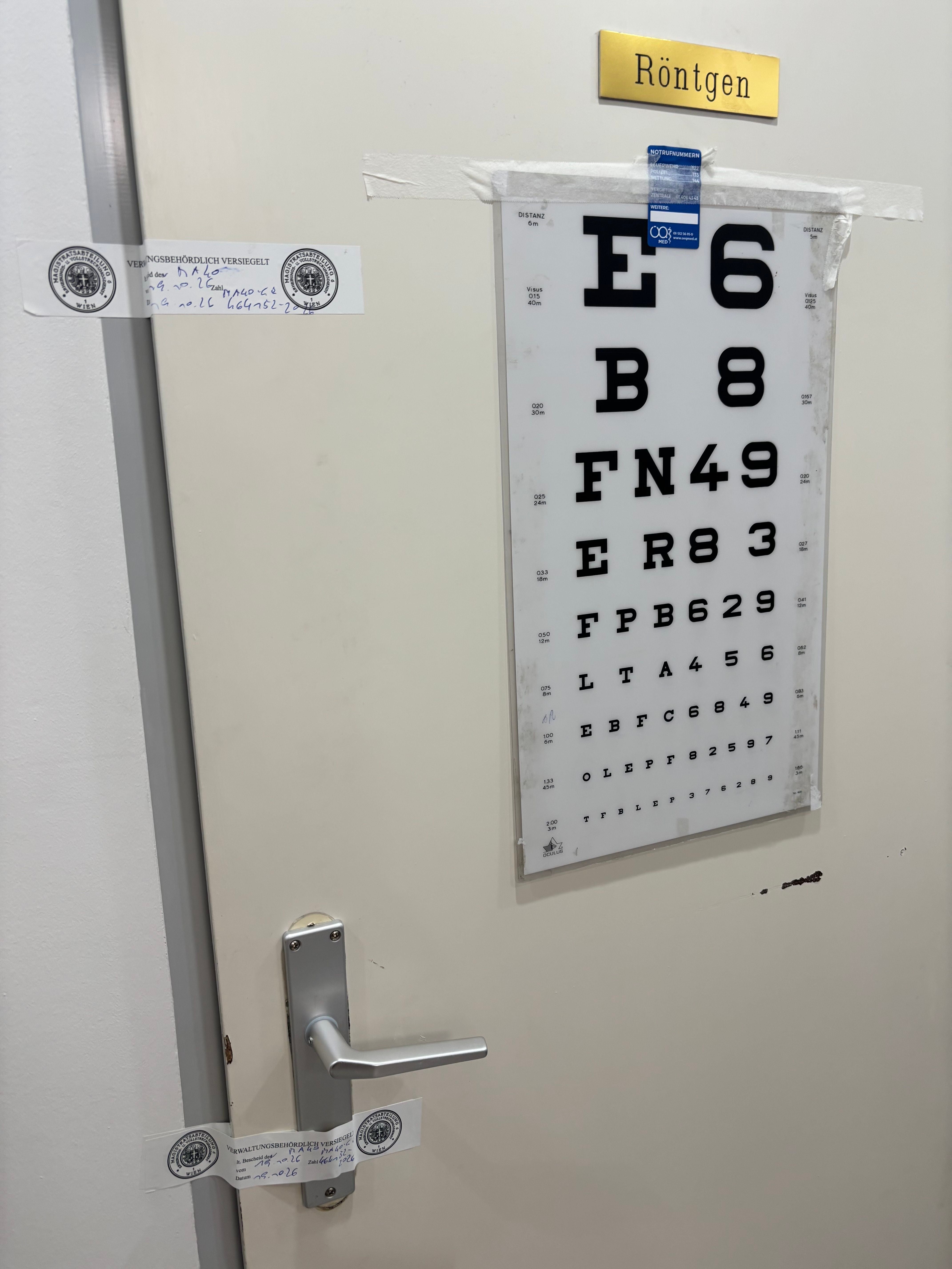 Tür mit Sehtafel zum Röntgenraum, behördlich versiegelt mit Siegelstreifen und Hinweisschild.