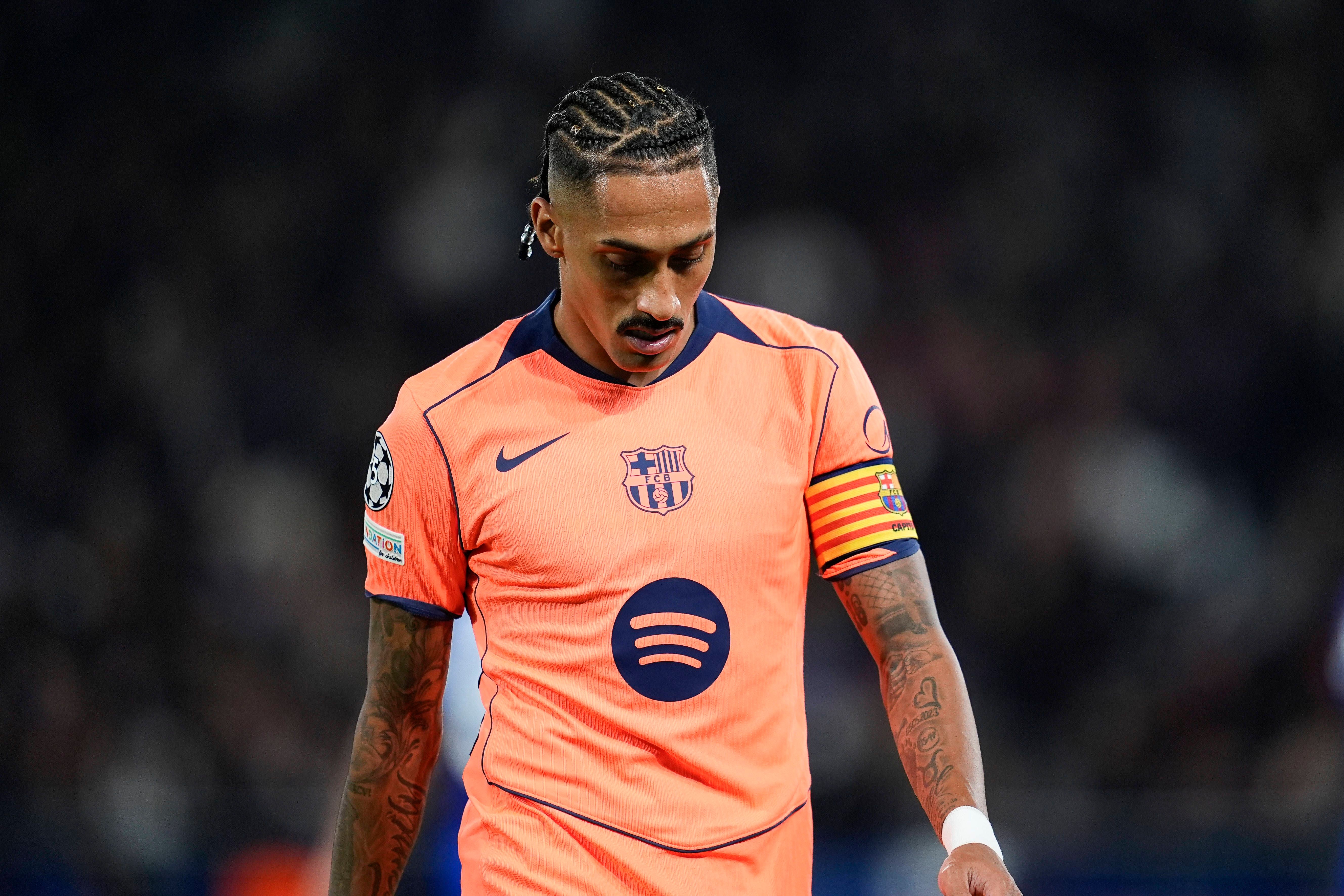 Fußballspieler im orangefarbenen FC-Barcelona-Trikot blickt während eines Spiels nach unten.