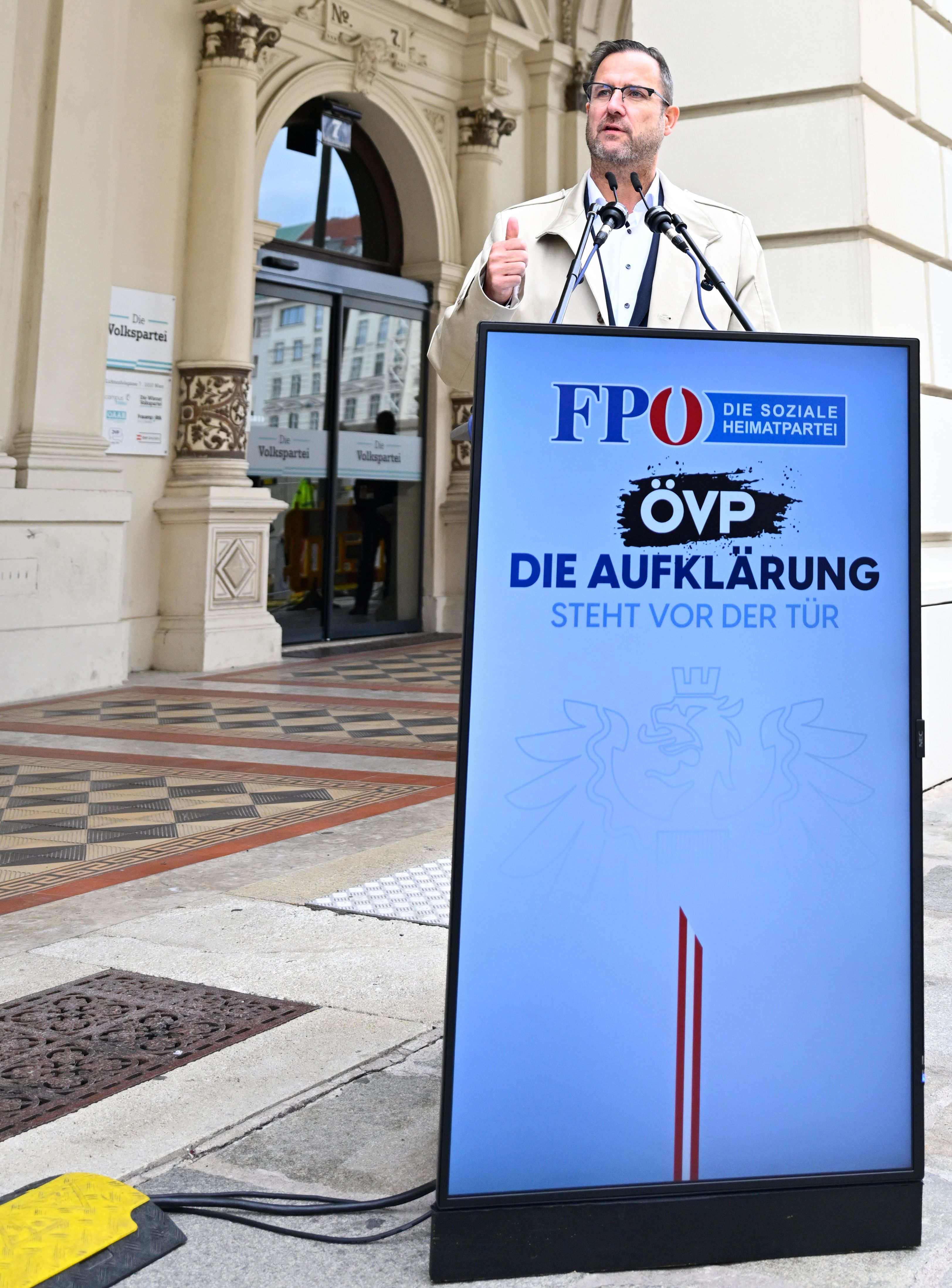 Ein Mann spricht bei einer Pressekonferenz am Rednerpult vor einem Gebäude in Wien.