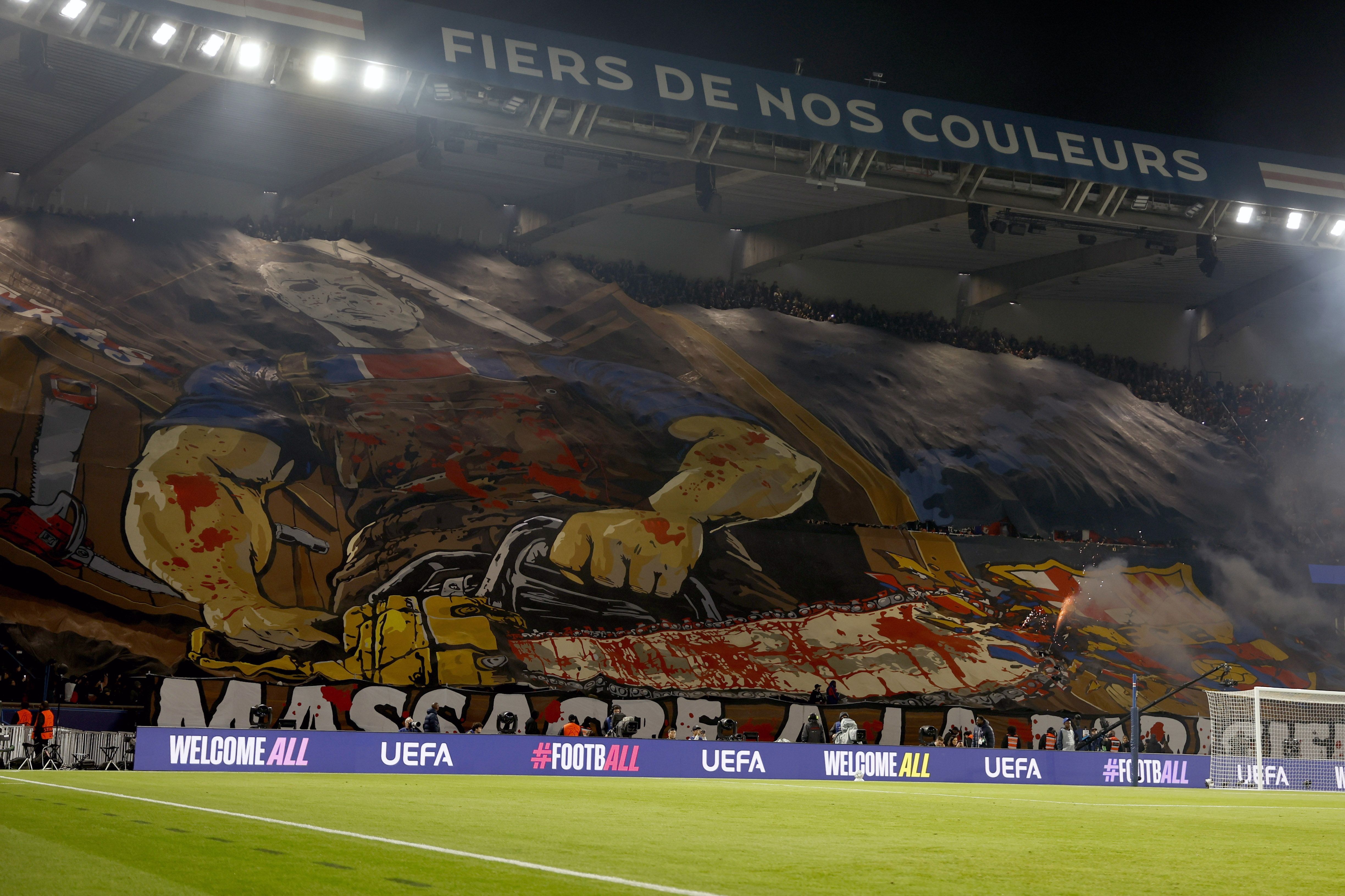 PSG-Fans zeigen ein blutiges Tifo mit Kettensägenmotiv im Stadion vor einem Champions-League-Spiel.