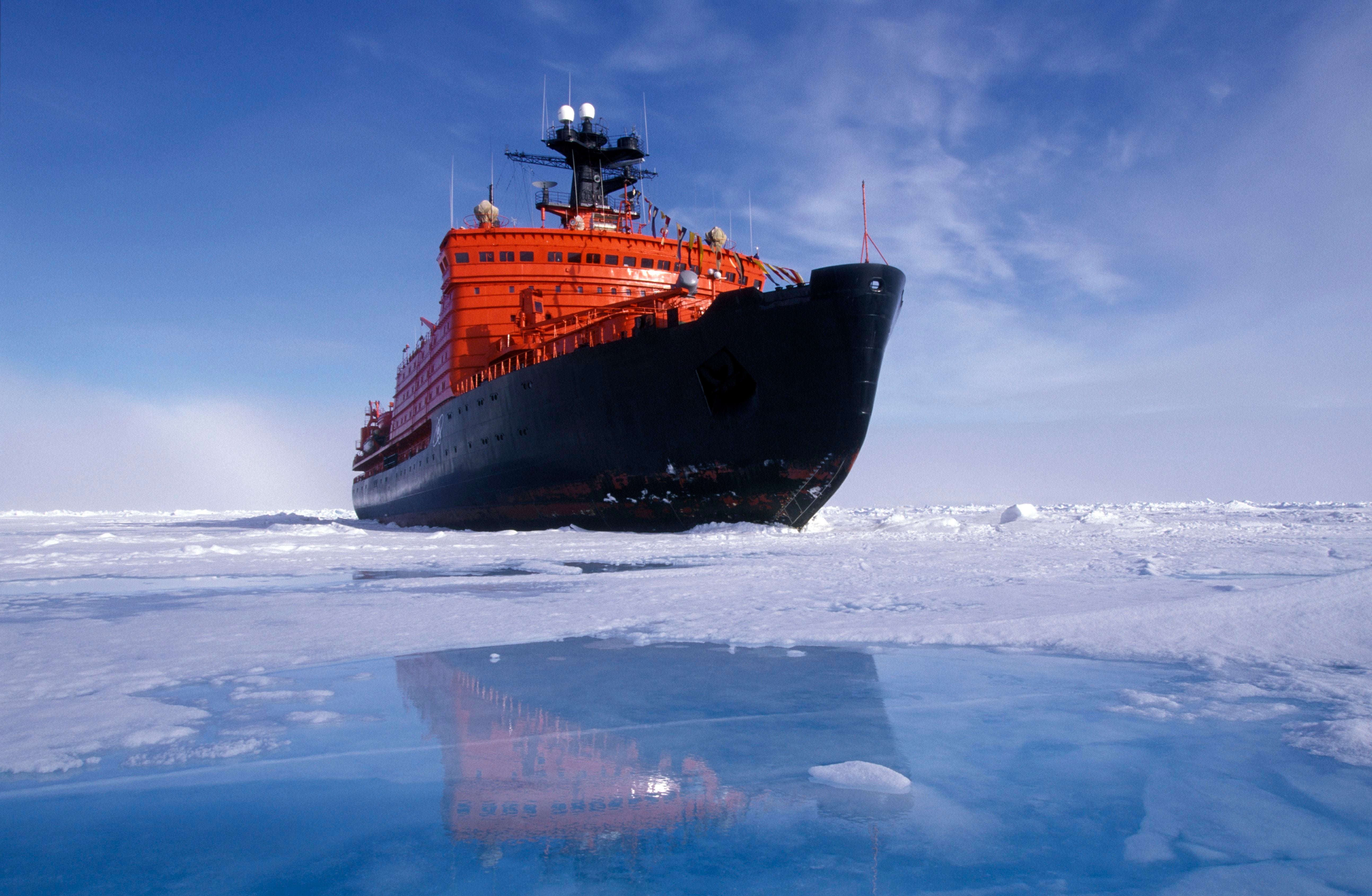 Russischer Eisbrecher am Nordpol spiegelt sich in einer Schmelzwasserpfütze auf dem Eis.