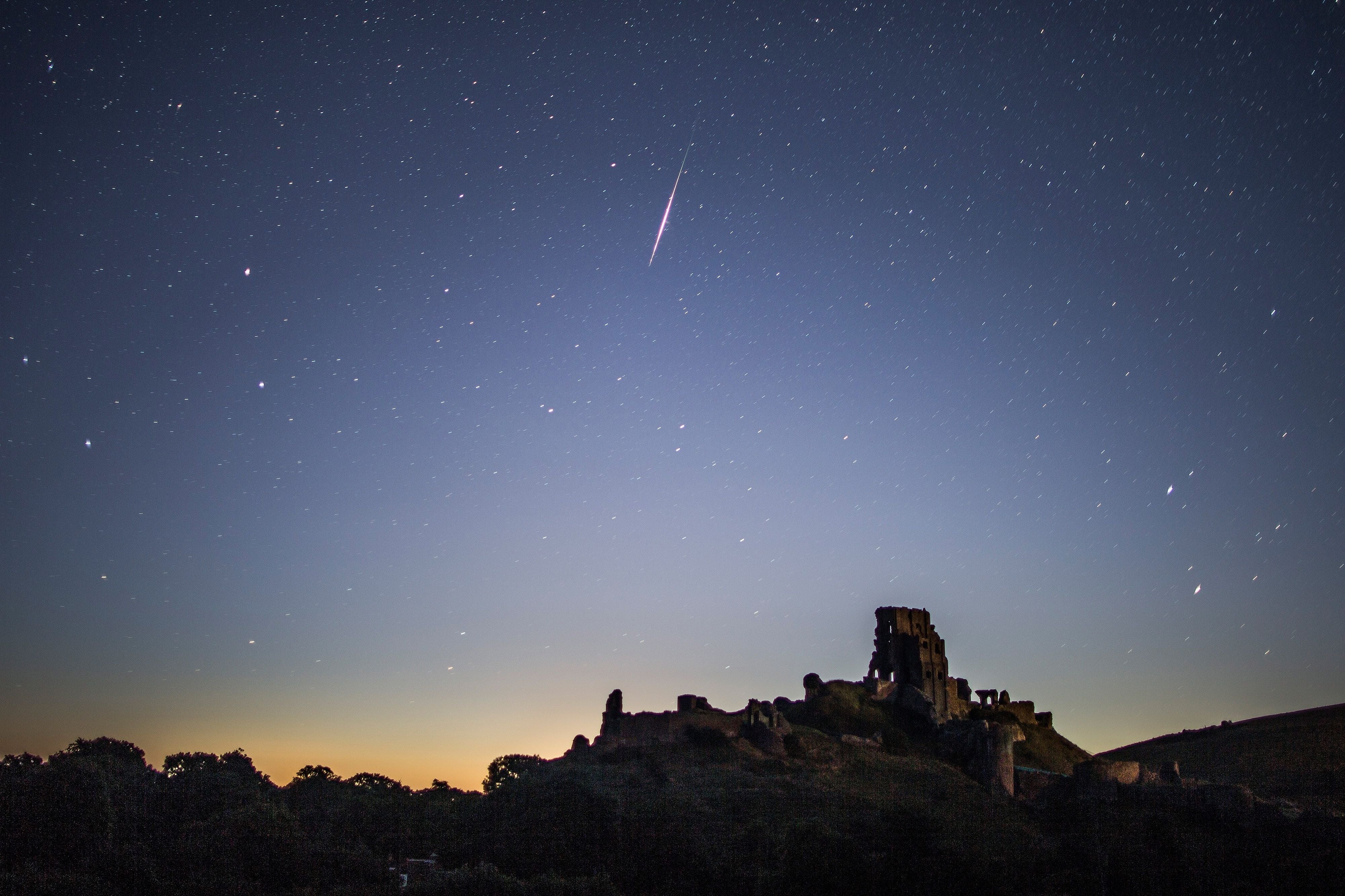 Eine Sternschnuppe leuchtet am Nachthimmel über der Ruine von Corfe Castle.