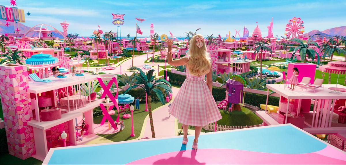 Frau in rosa Kleid blickt auf eine farbenfrohe, fantasievolle Stadt voller Pink und Pastelltönen.