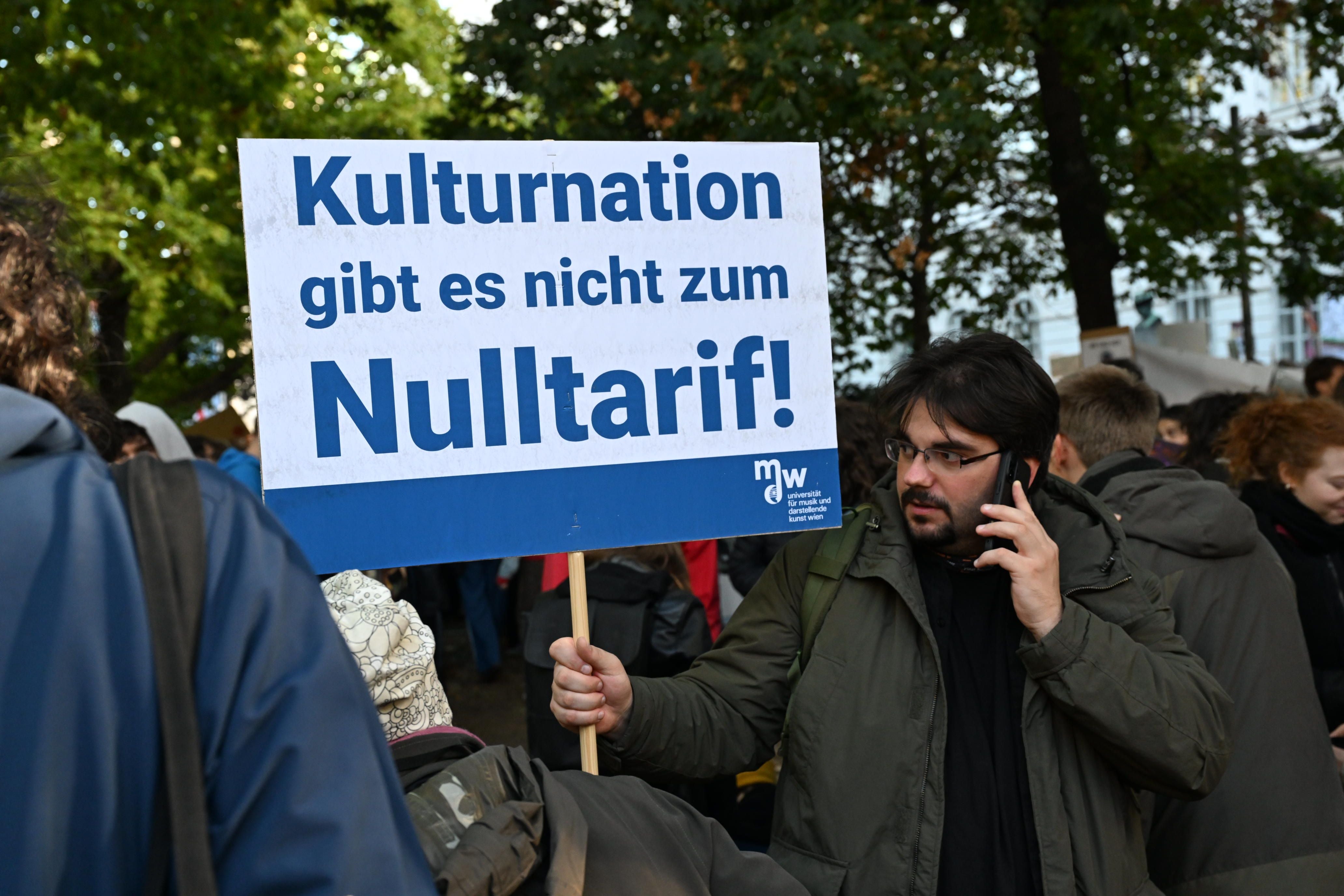 Mann hält bei einer Demonstration ein Schild mit der Aufschrift „Kulturnation gibt es nicht zum Nulltarif!“.