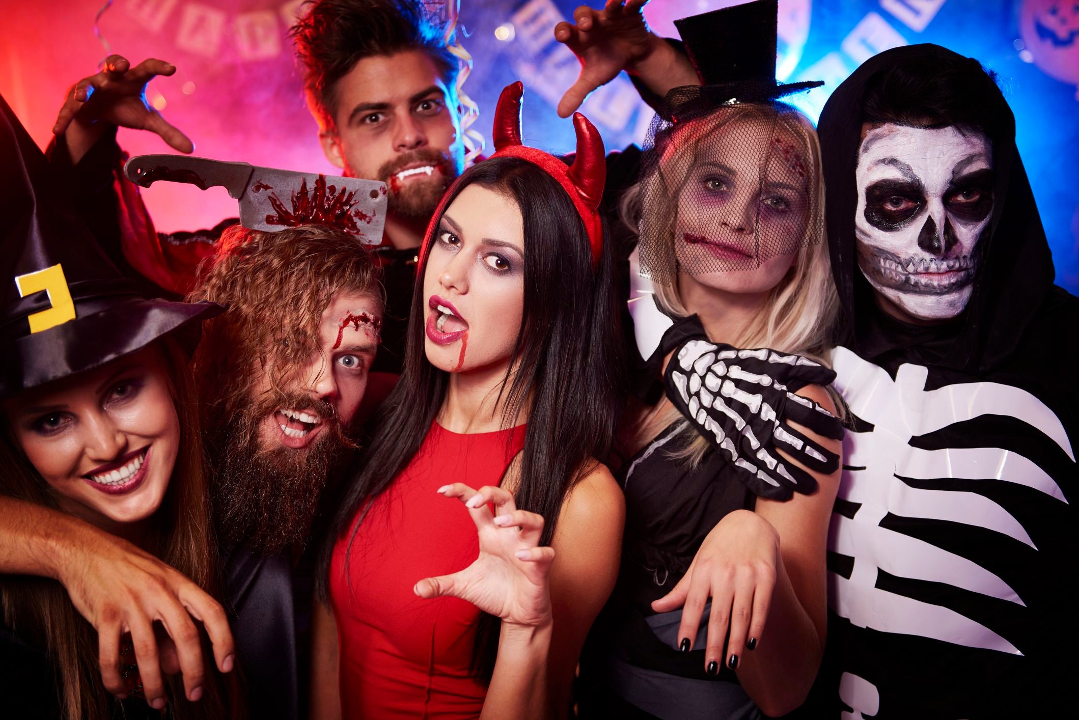 Sechs junge Erwachsene in gruseligen Halloween-Kostümen und Make-up posieren für ein Foto.