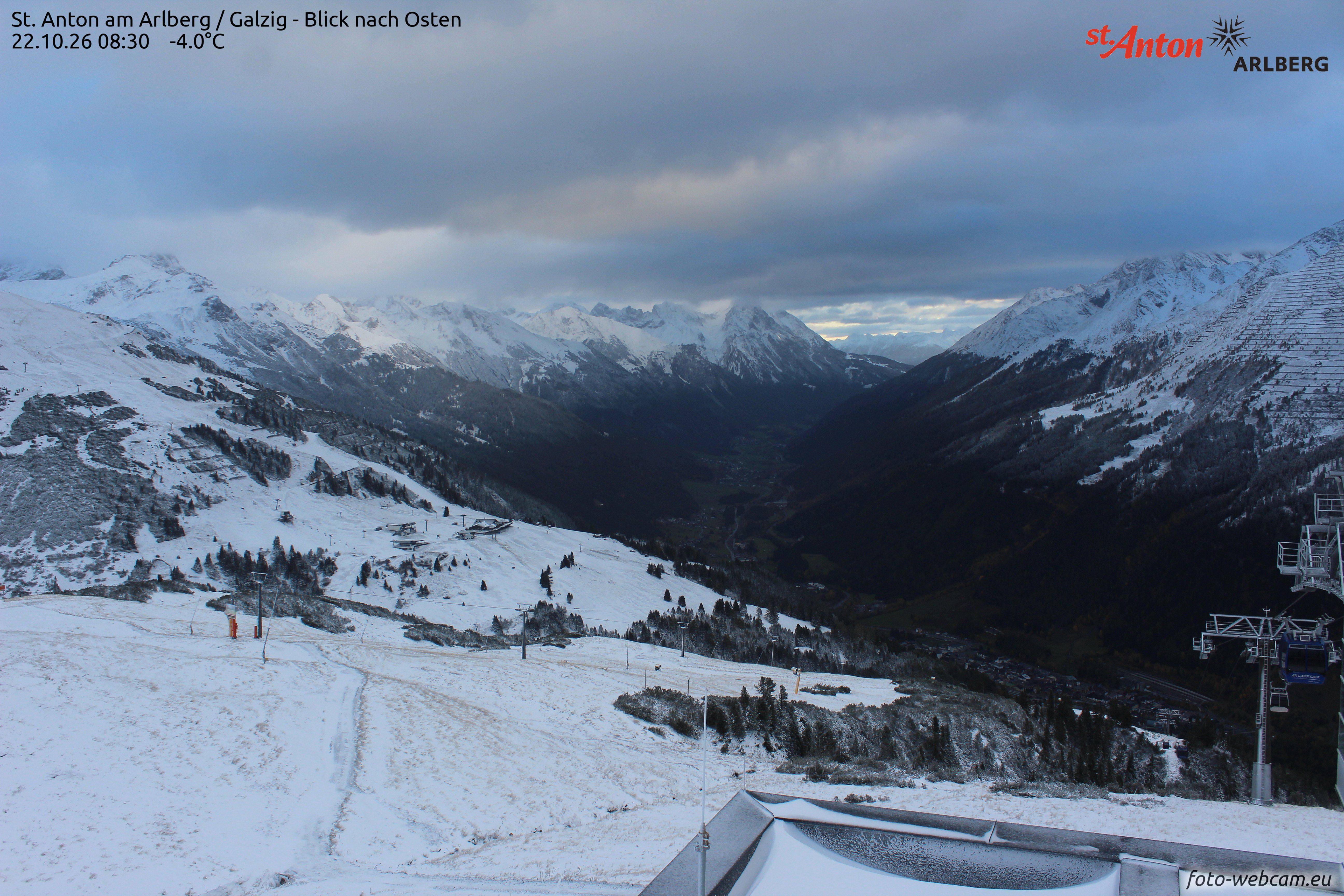 Blick auf verschneite Berge und ein Tal in St. Anton am Arlberg bei bewölktem Himmel.
