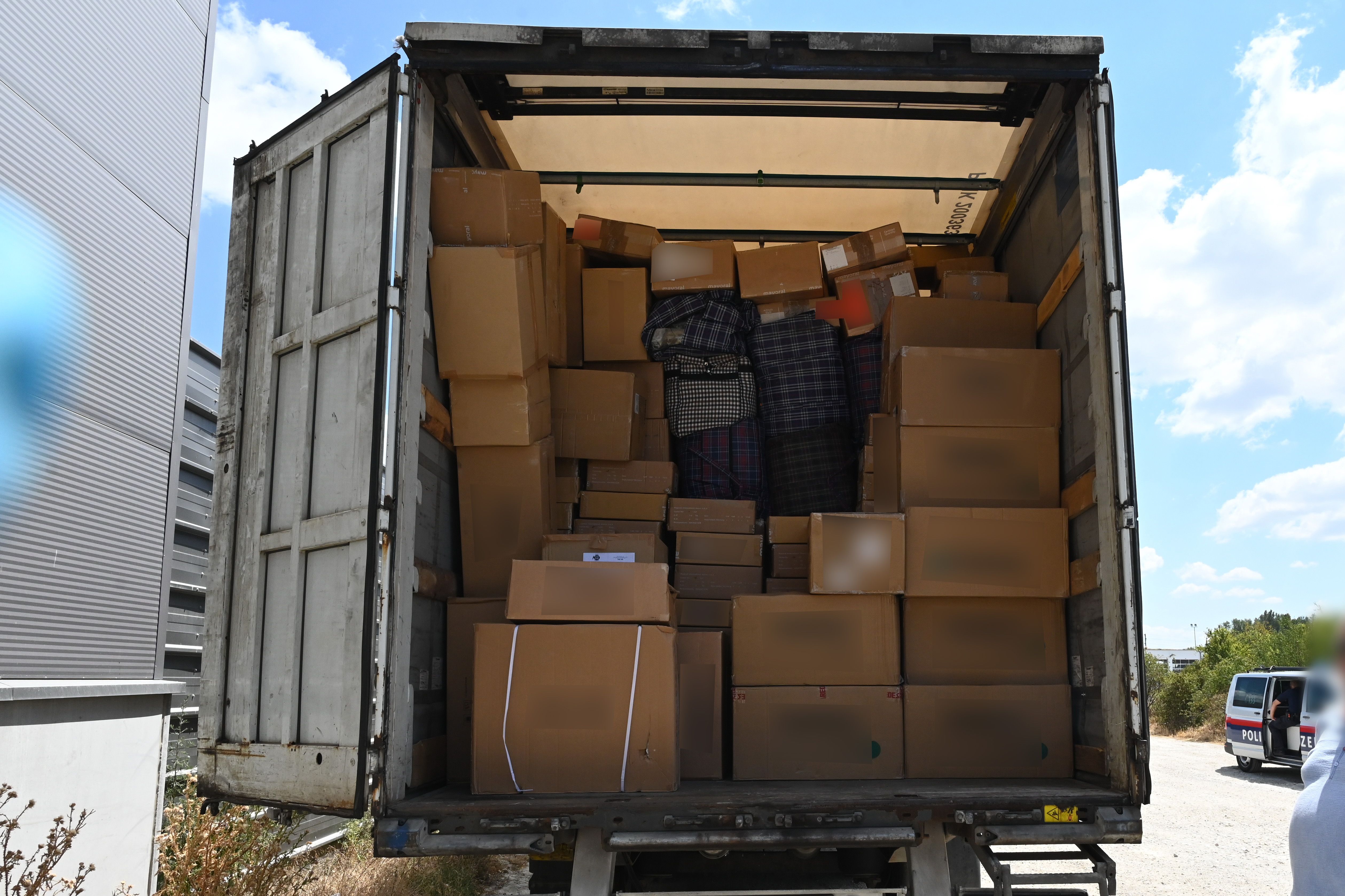 Ein Lkw mit geöffnetem Heck, voll beladen mit zahlreichen Kartons und Taschen.