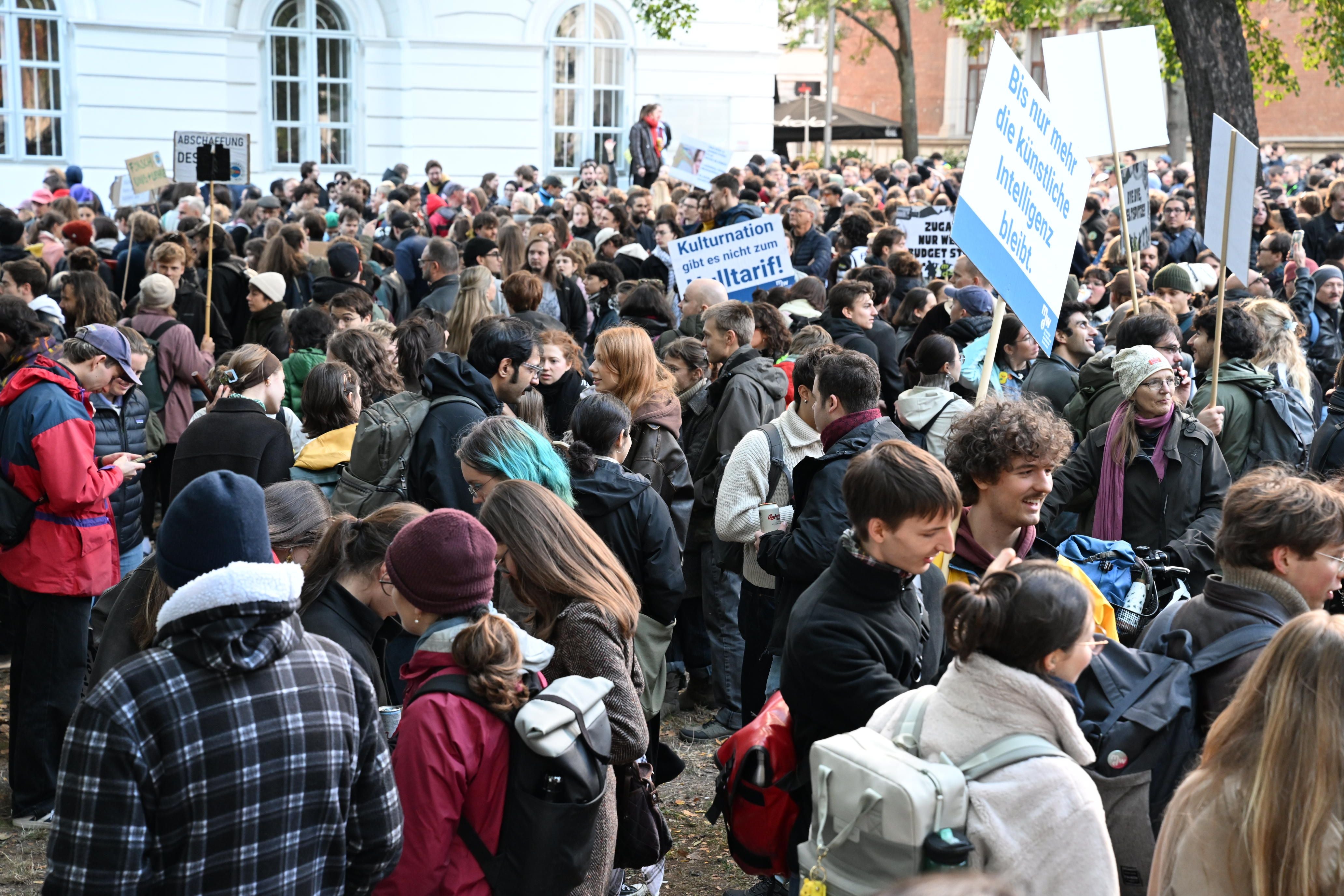 Viele Menschen versammeln sich bei einer Uni-Demo mit Bannern und Schildern im Freien.
