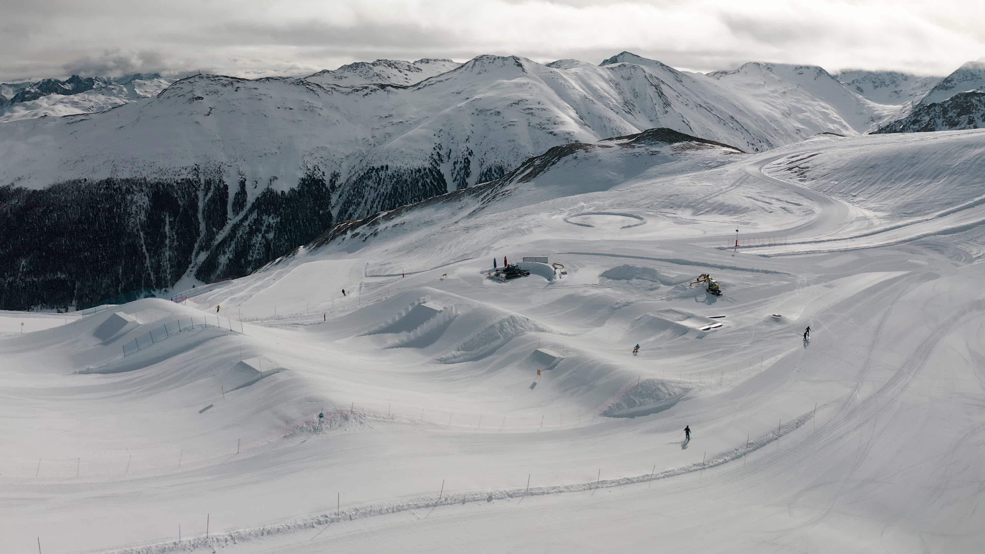 Skifahrer und Snowboarder fahren auf schneebedeckten Pisten im Gebirge bei Livigno, Italien.