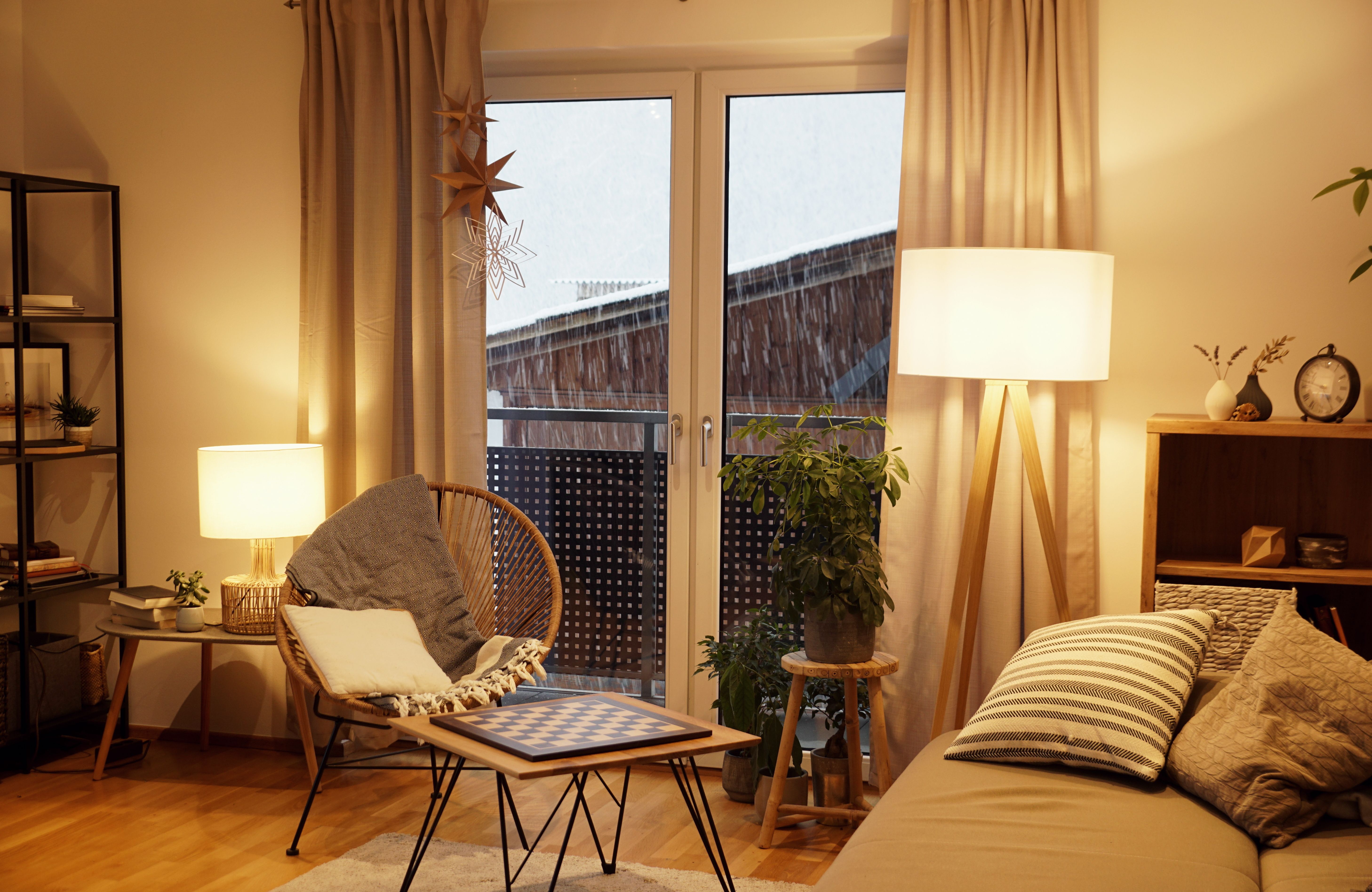 Gemütliches Wohnzimmer im skandinavischen Stil mit Sesseln, Stehlampe und winterlichem Ausblick.