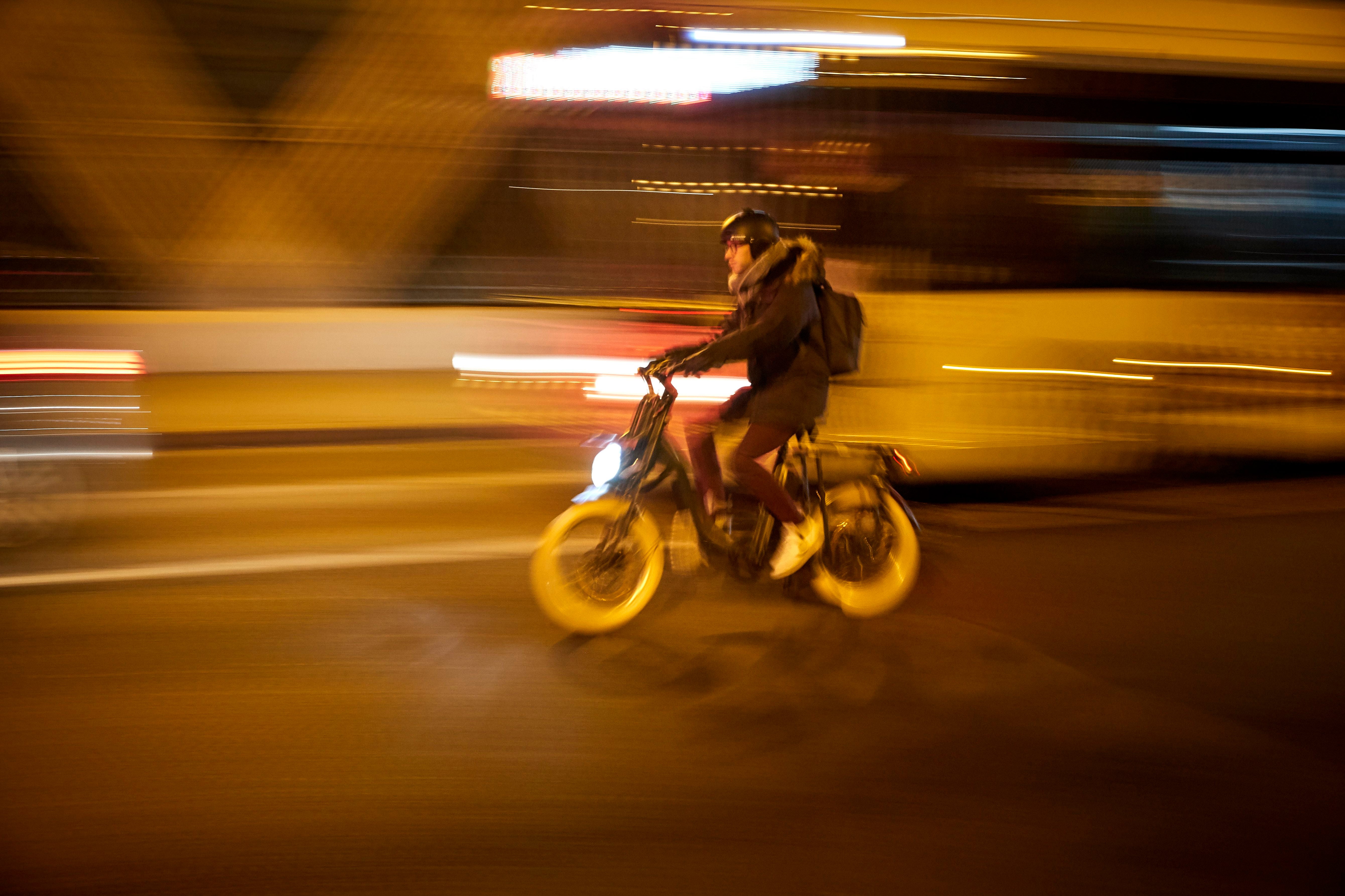 Eine Person fährt nachts mit einem Elektrofahrrad durch die beleuchtete Stadt.