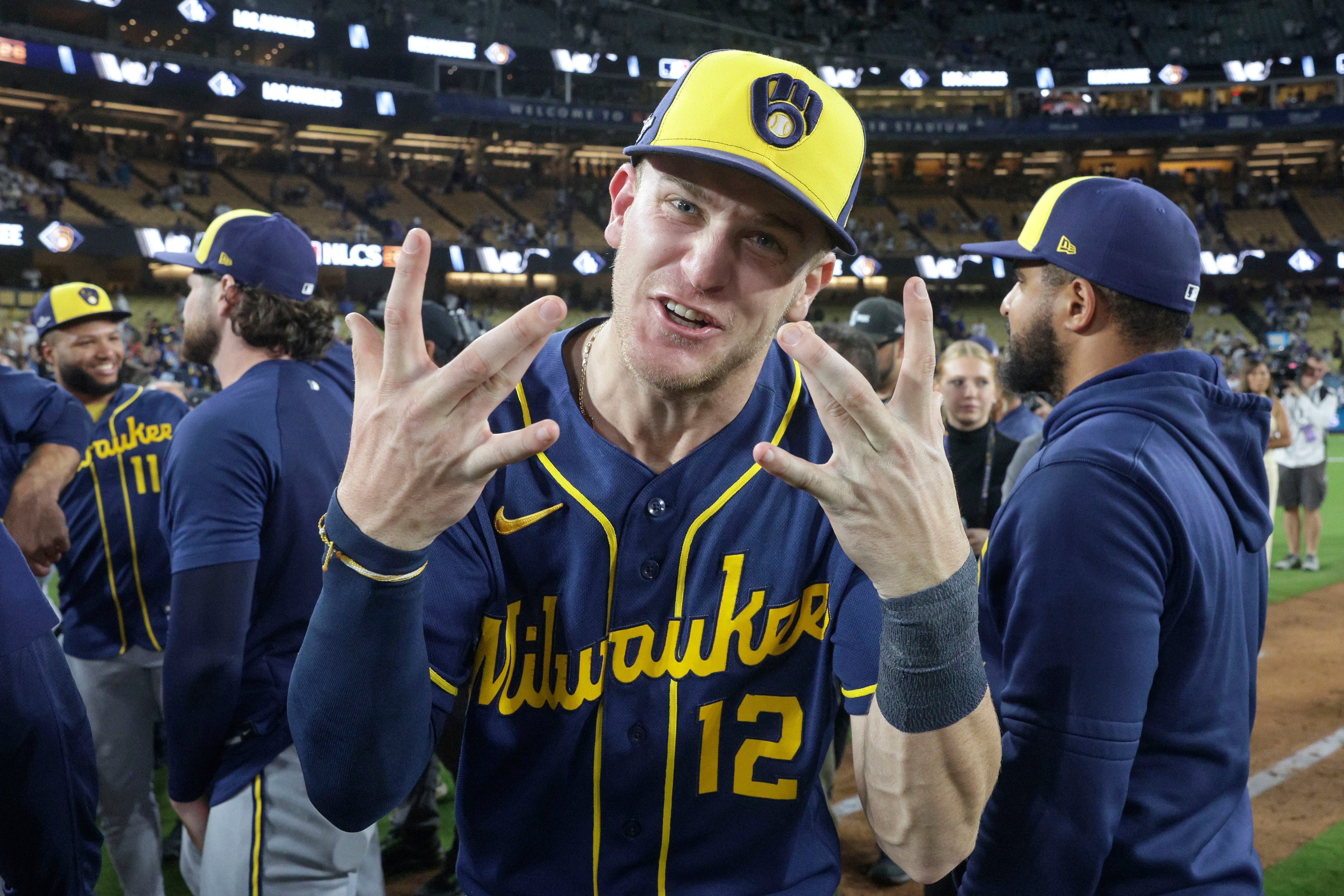 Ein Profi der Milwaukee Brewers feiert im blau-gelben Trikot und mit Baseballcap den Aufstieg ins MLB-Finale mit Jubelgesten vor seinen Teamkollegen auf dem Feld.