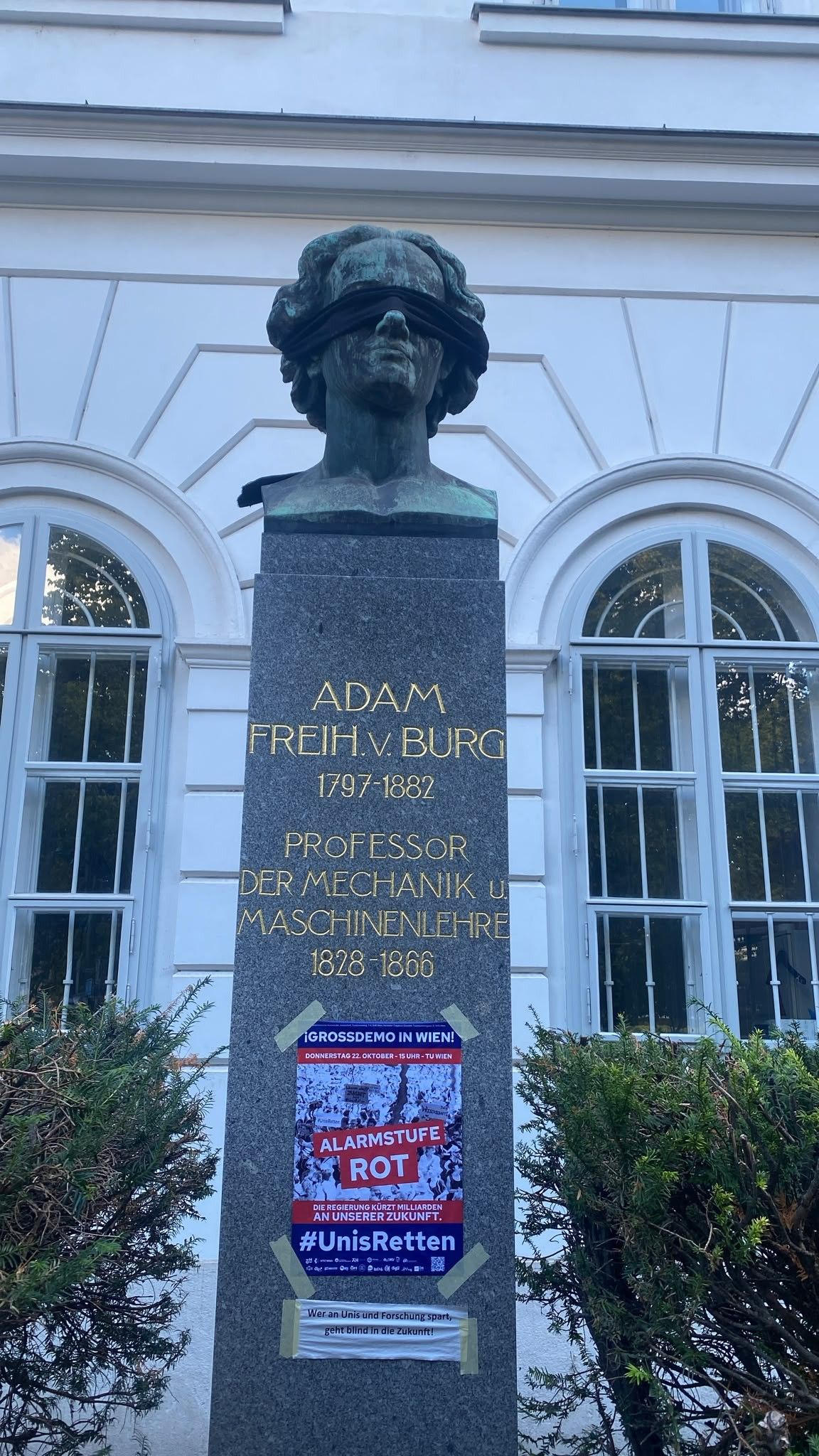 Büste mit verbundenen Augen, darunter ein Demo-Plakat mit dem Schriftzug „Alarmstufe Rot“.
