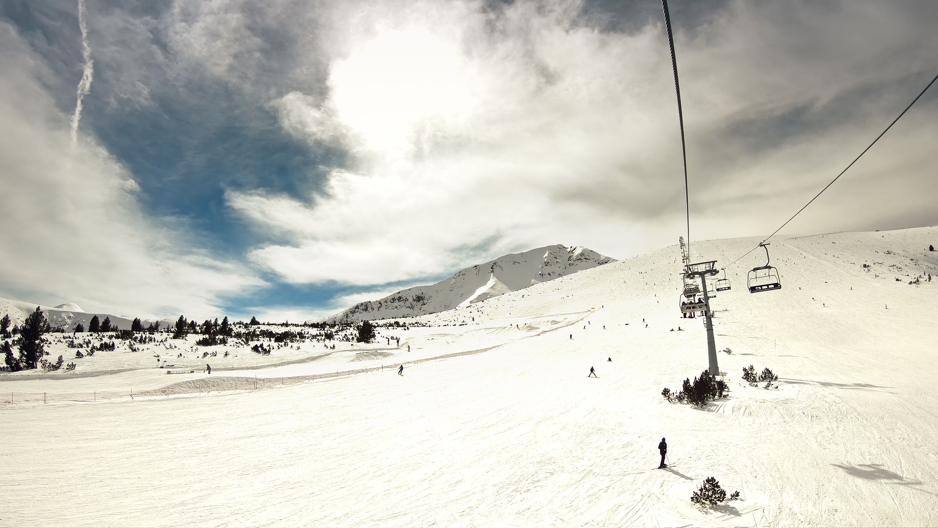 Blick von einem Sessellift auf schneebedeckte Piste mit Skifahrern und Snowboardern in Bansko, Bulgarien.