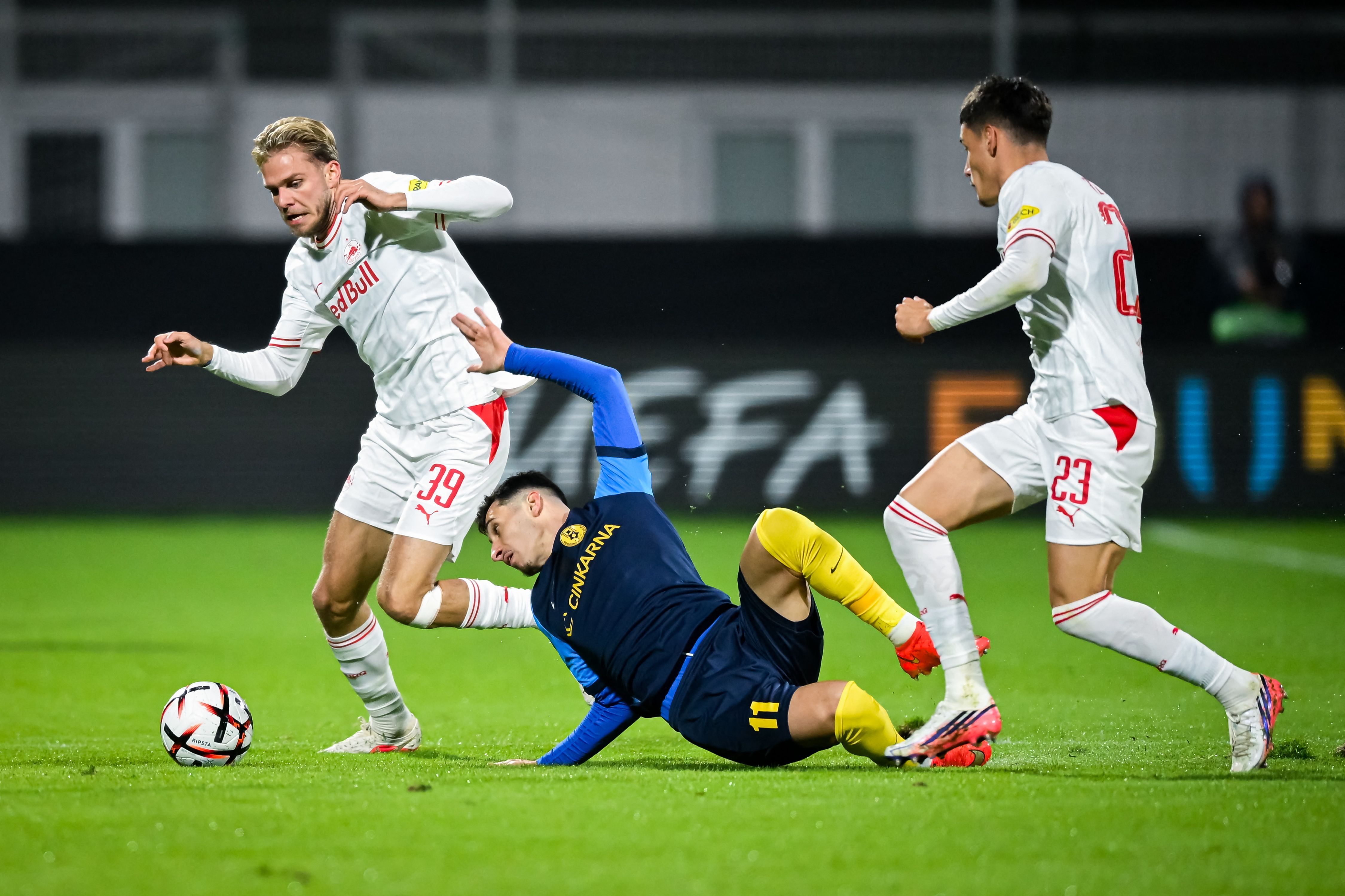 Zwei Spieler von Salzburg kämpfen mit einem Spieler von Celje während eines Fußballspiels um den Ball.