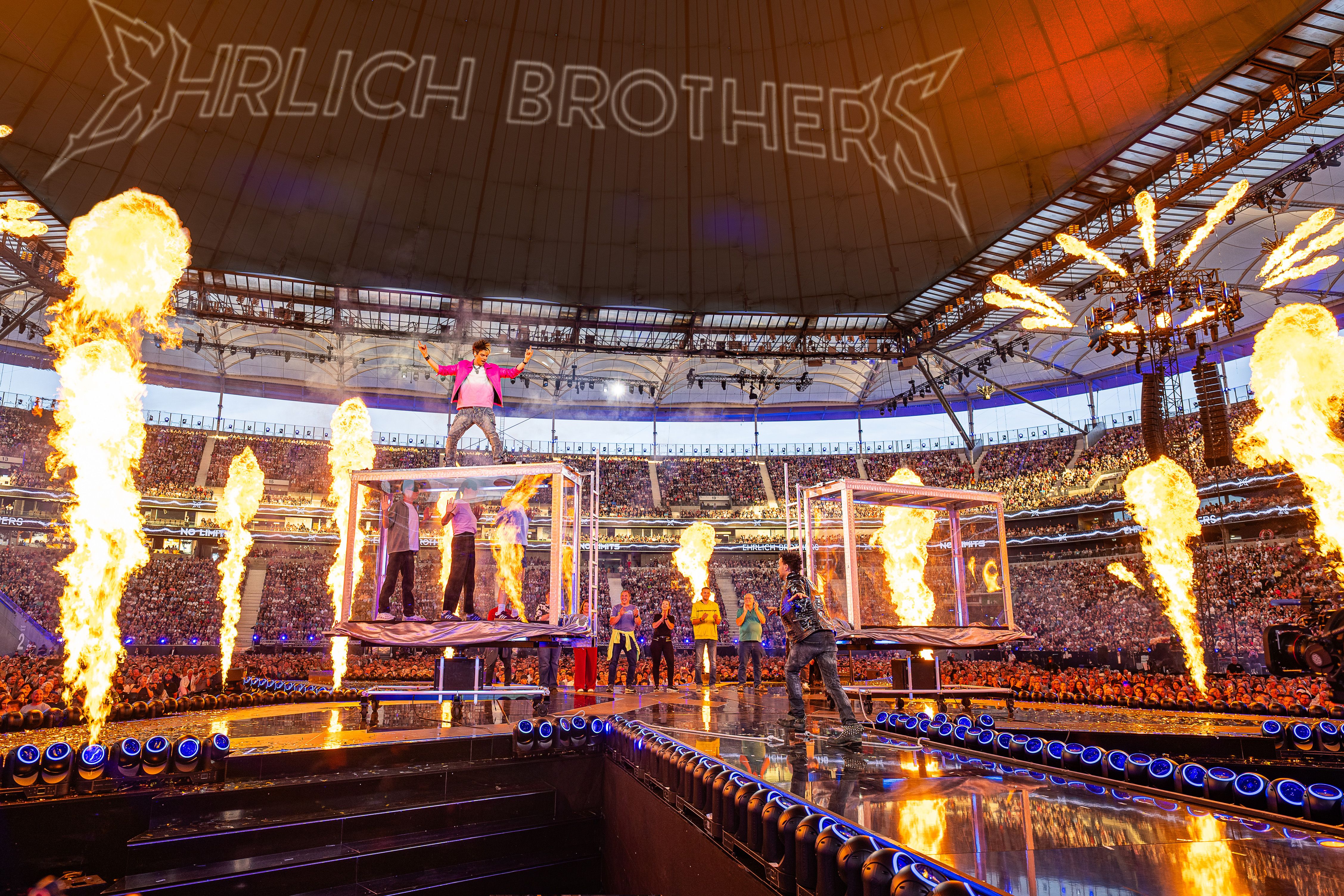 Große Bühnenshow mit Pyrotechnik, zwei Glaskästen und einem Künstler, der auf einem Kasten steht.